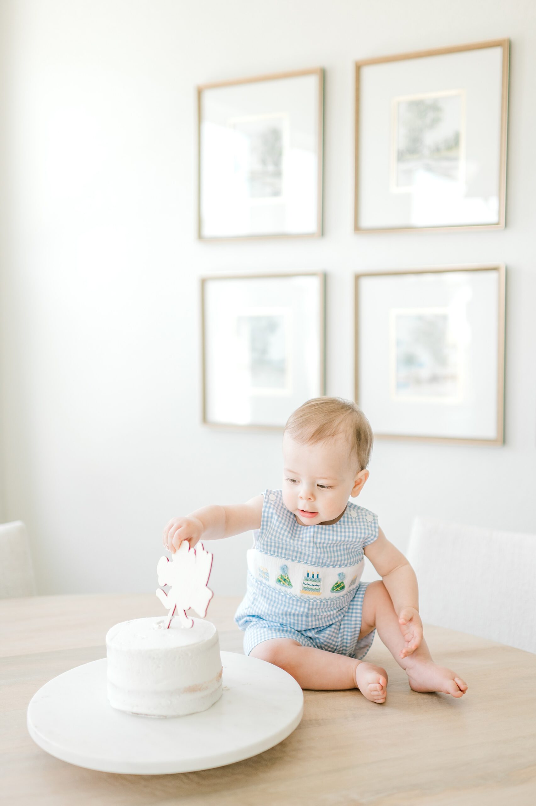 little boy sits on table and pokes at cake 