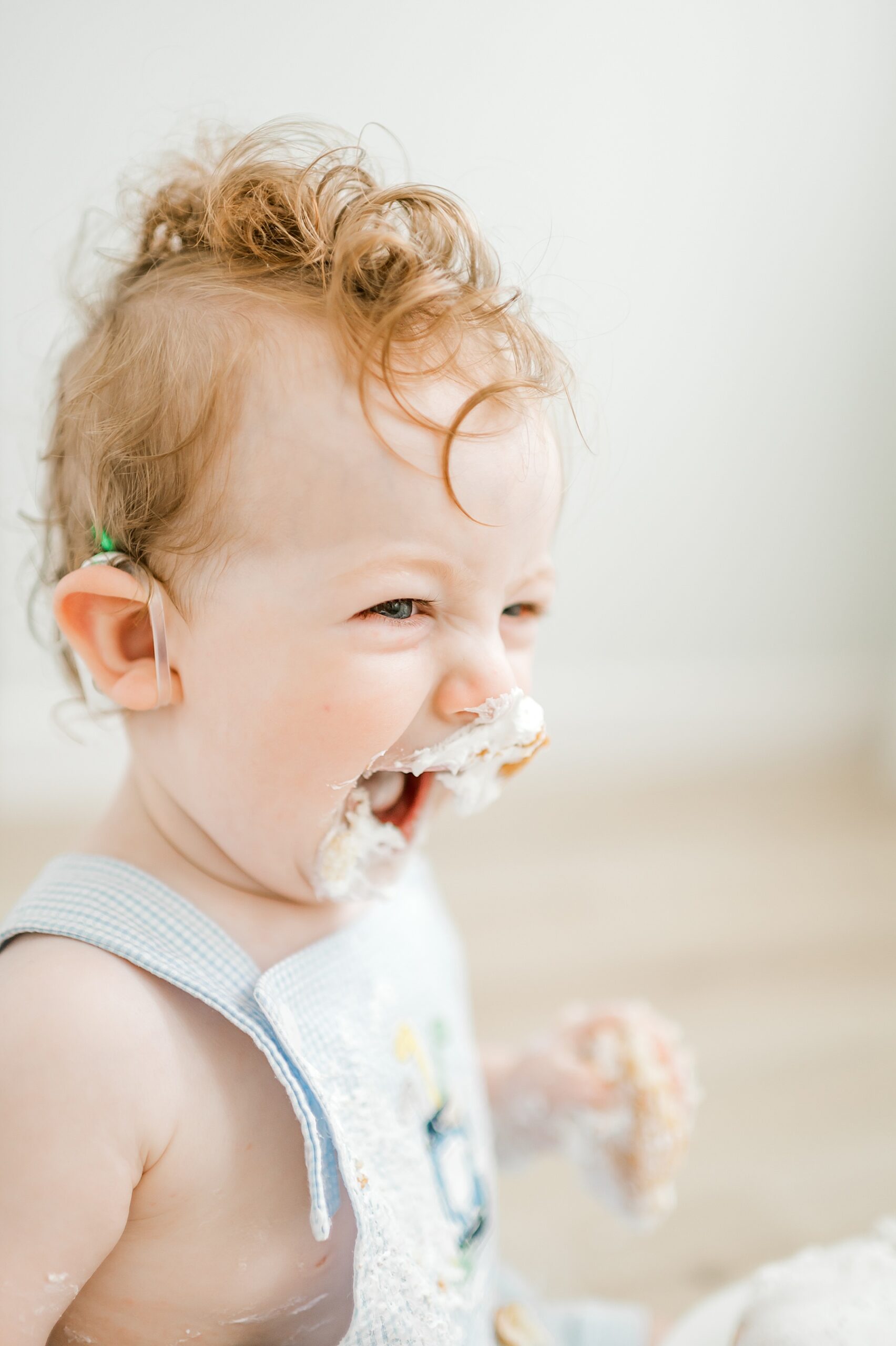 little boy laughs during cake smash