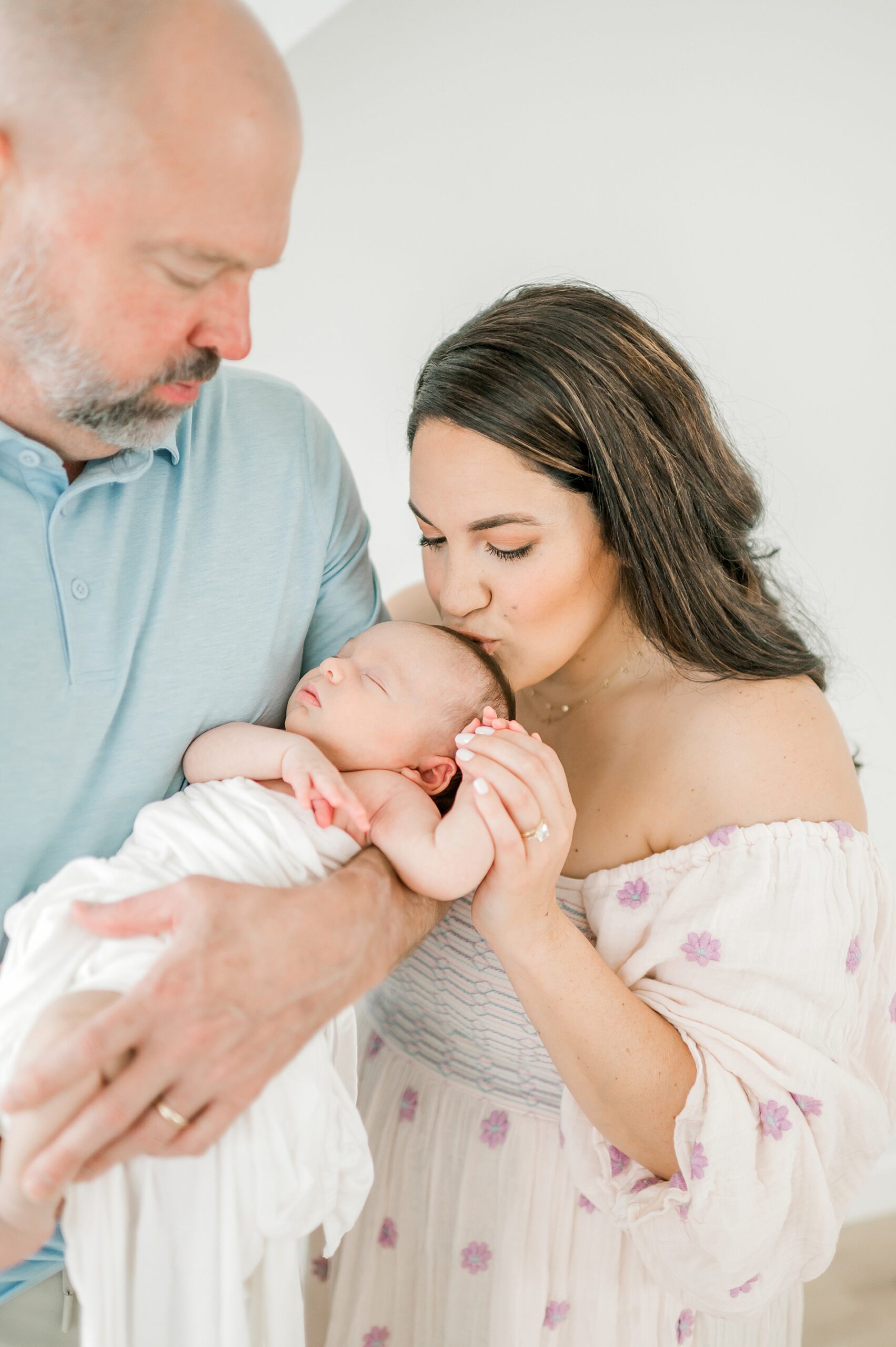 dad holds newborn and mom kisses her head