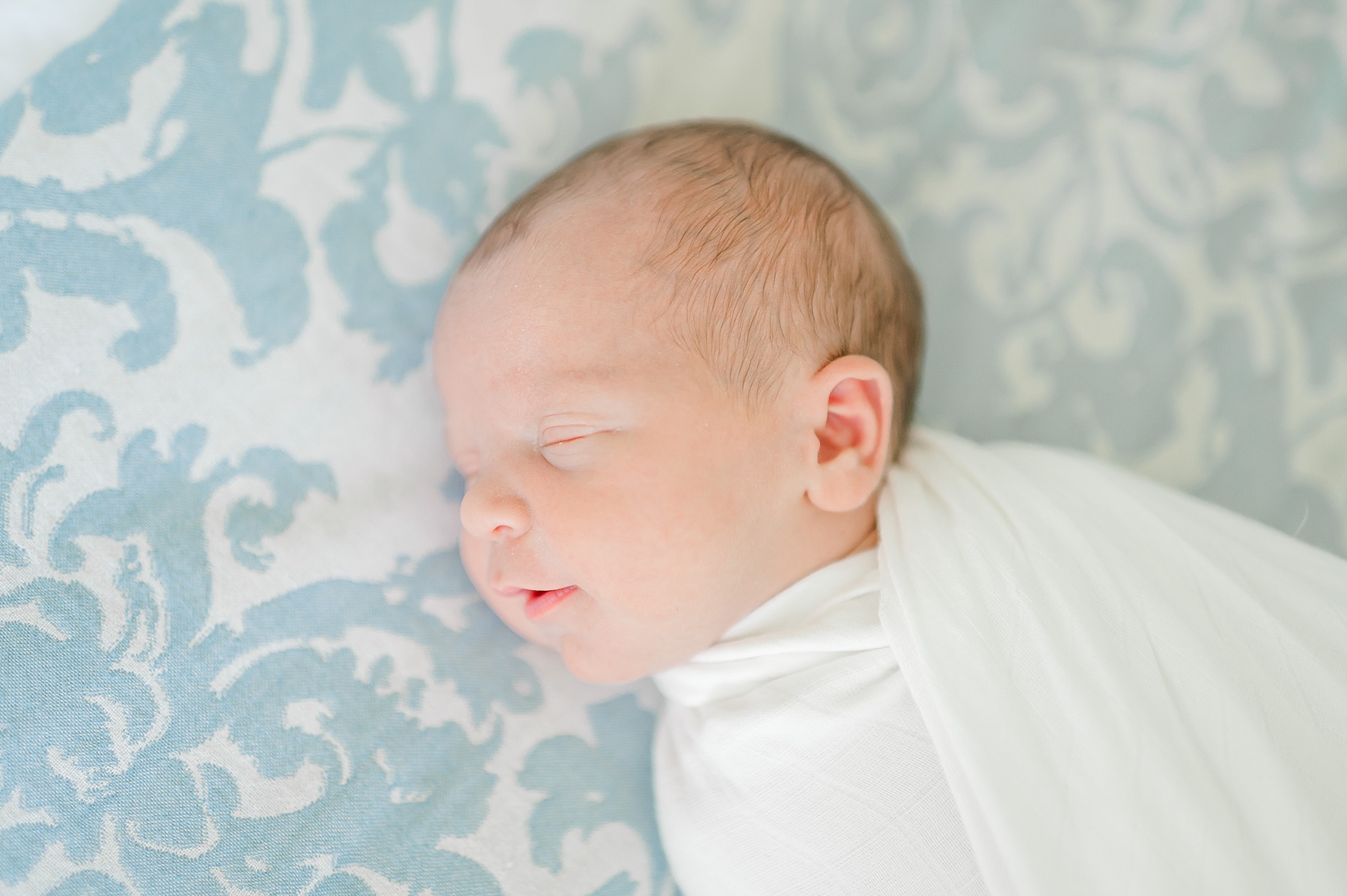 sleepy newborn swaddled in white