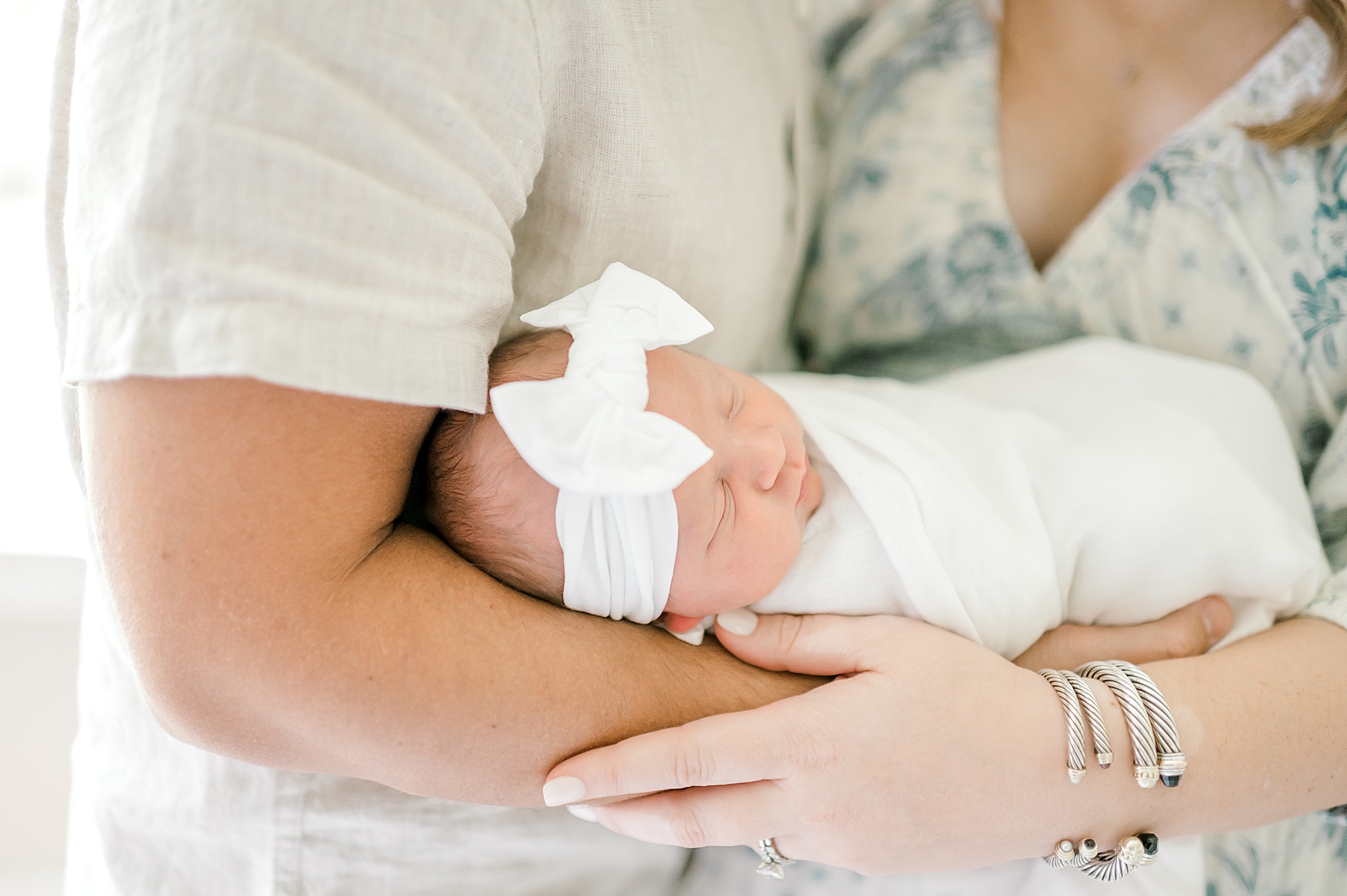 newborn girl swaddled in white with white bow 