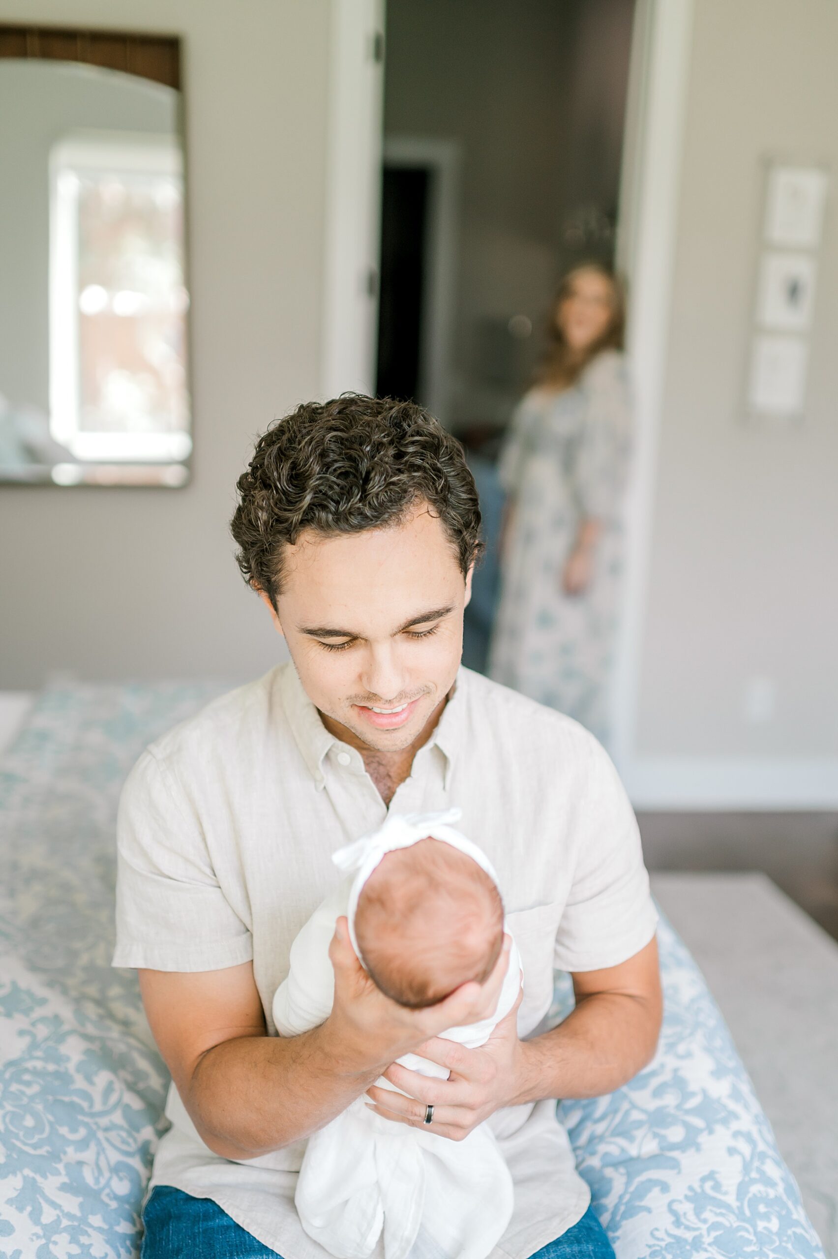 mom looks on as her husband holds newborn girl 