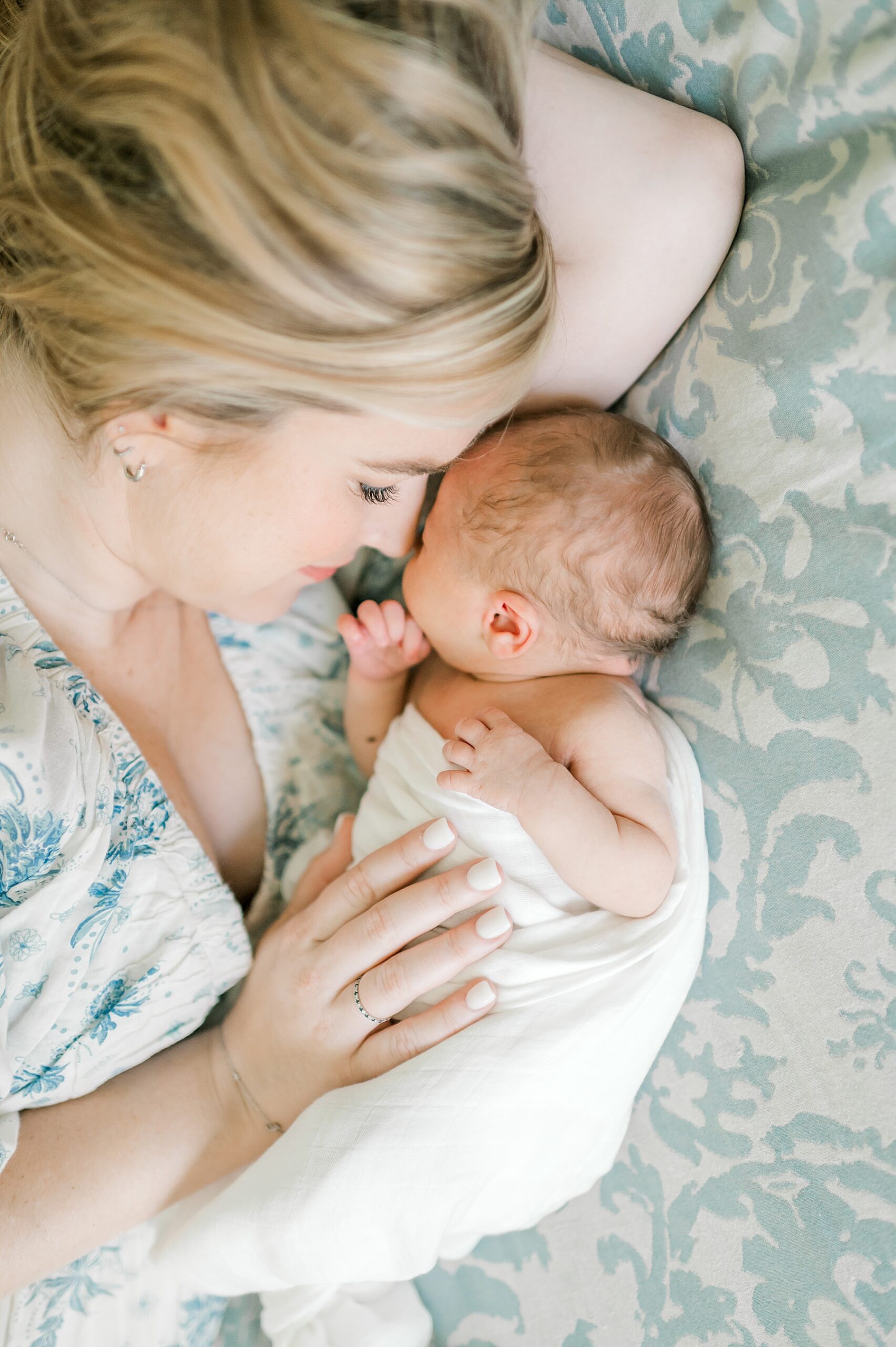 mom cuddles with newborn on bed