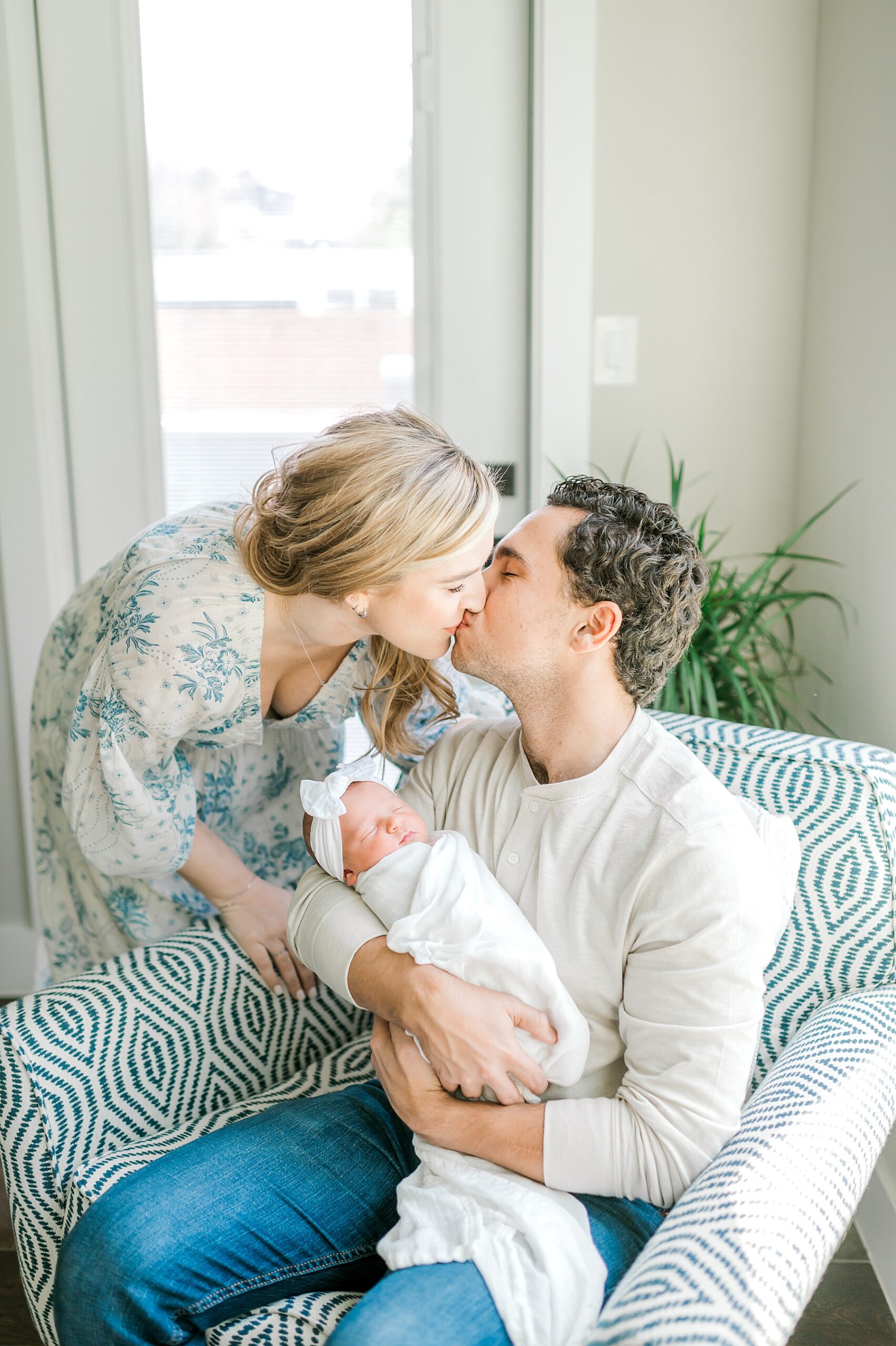 new parents kiss as they hold baby girl