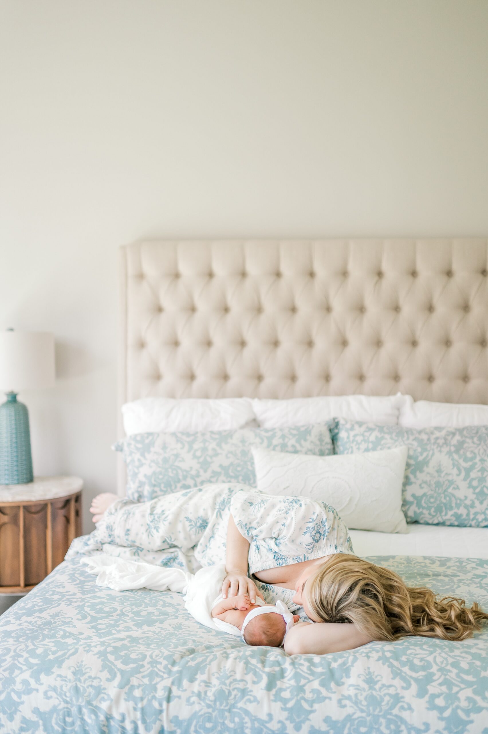 mom cuddles close to newborn on bed from Natural Light In-Home Lifestyle Newborn Session