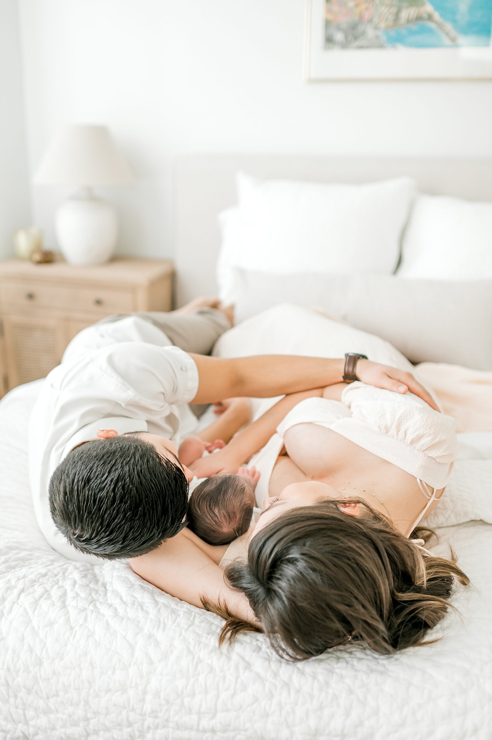 parents lay on bed with newborn girl