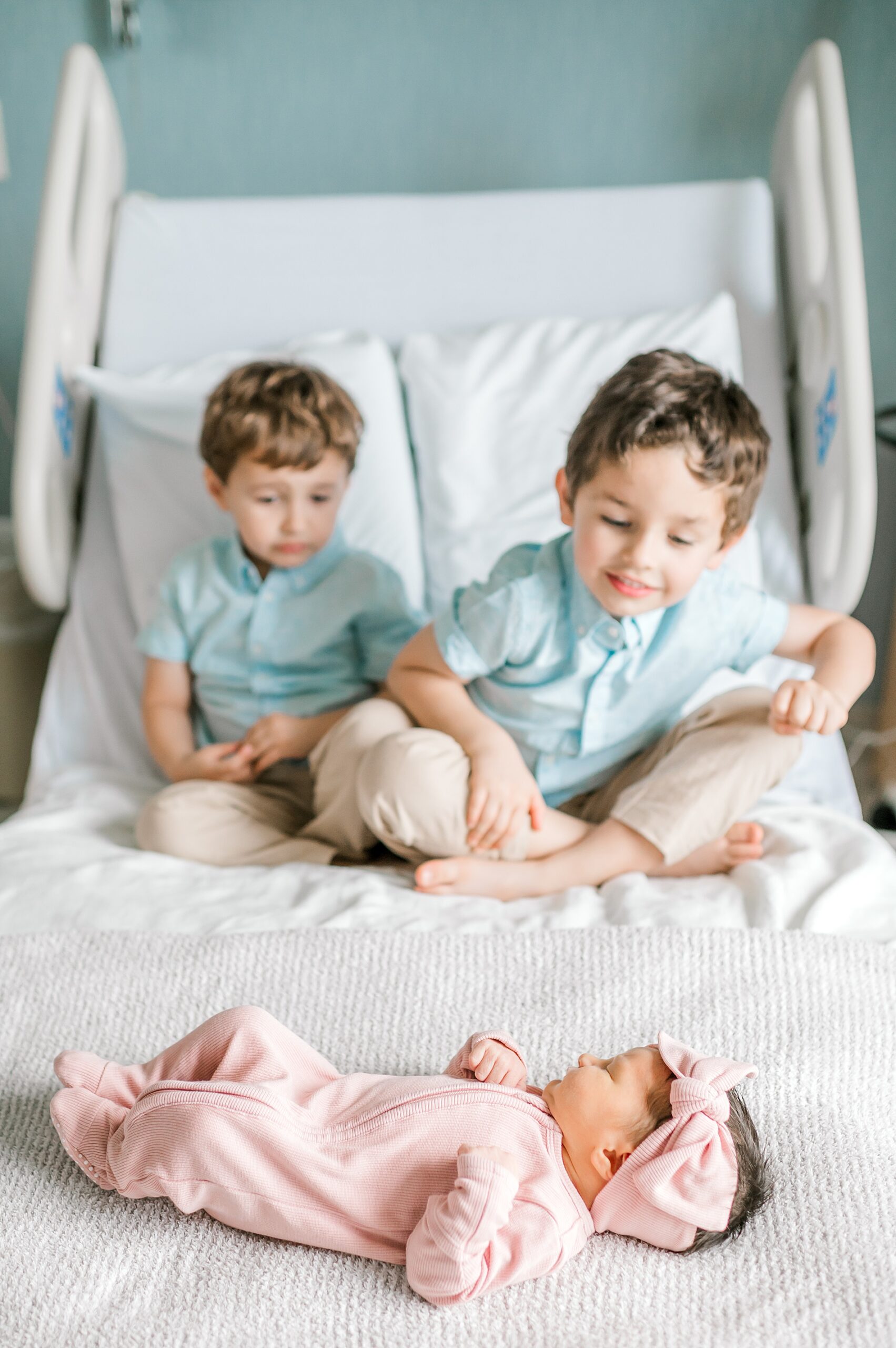 big brothers look at their newborn sister