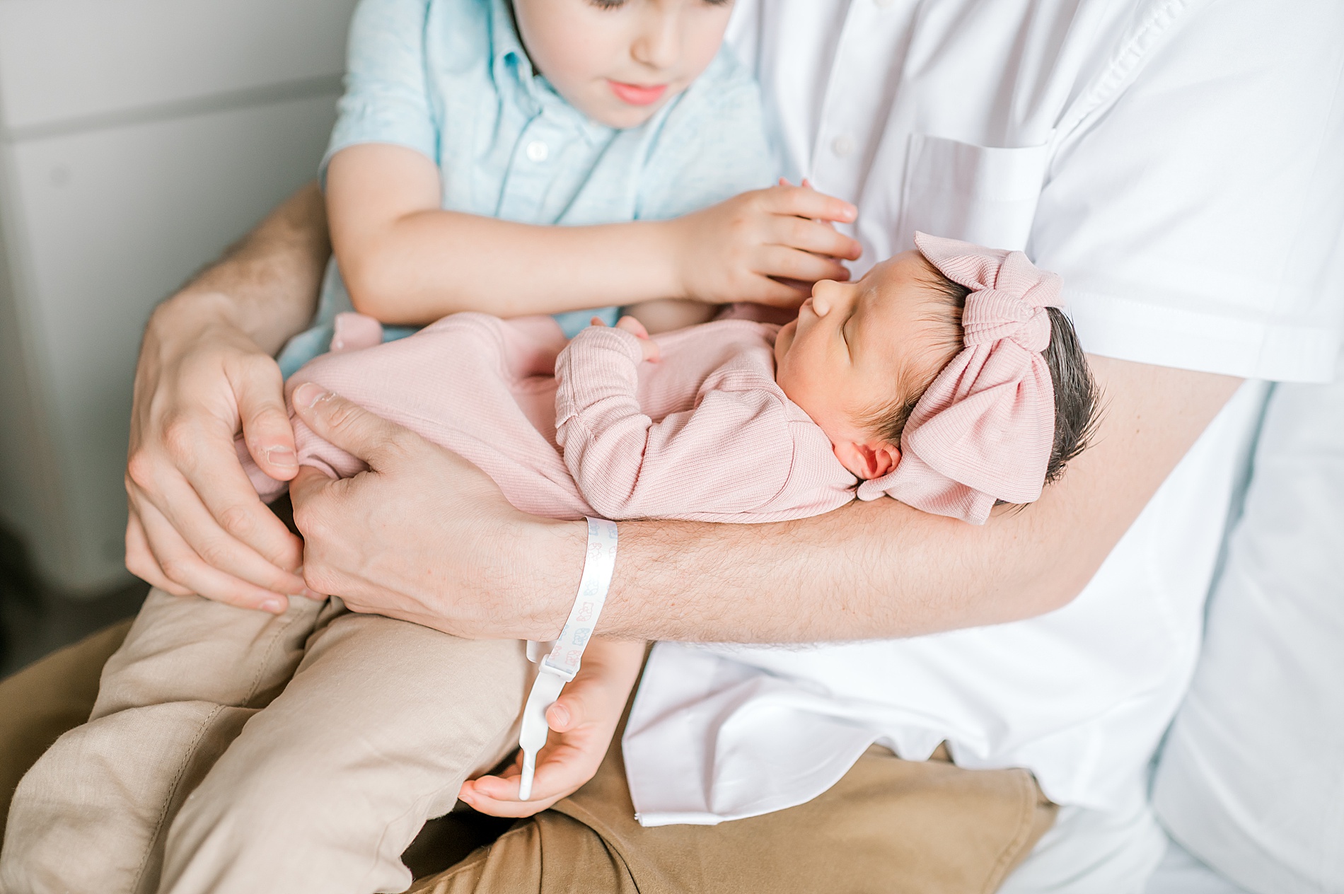 dad and brother hold newborn sister