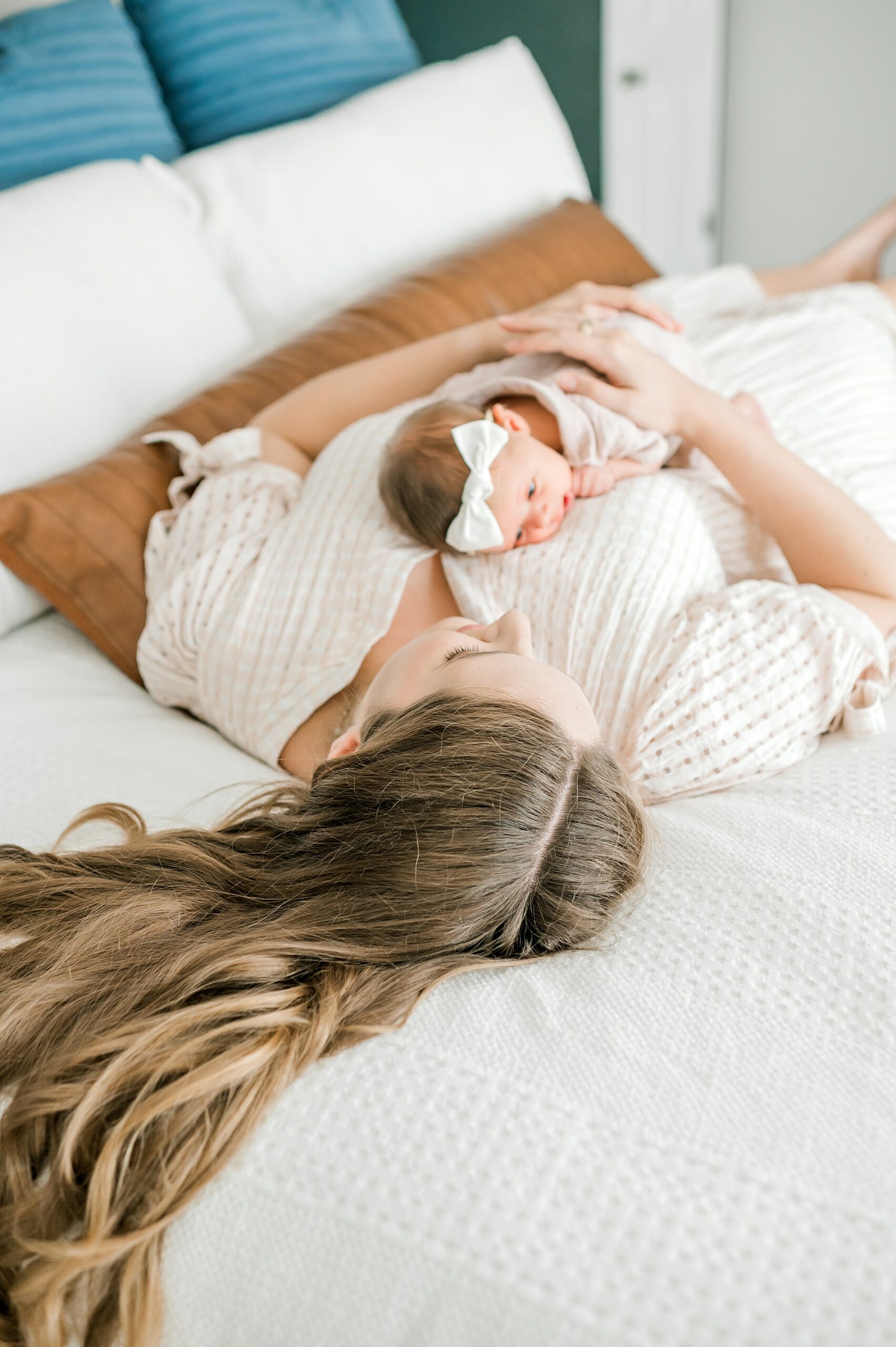 mom lays on bed with newborn 