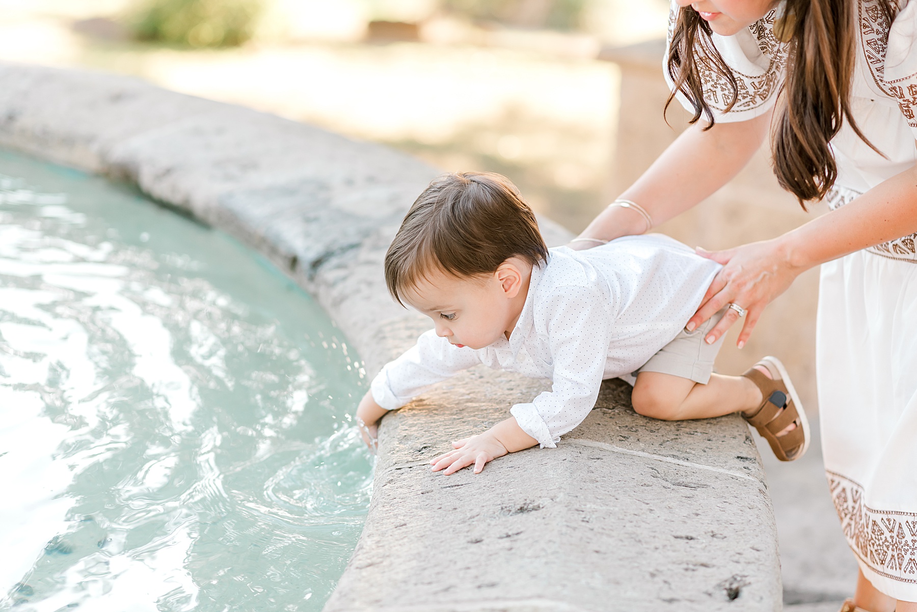 little boy touches water in fountain 