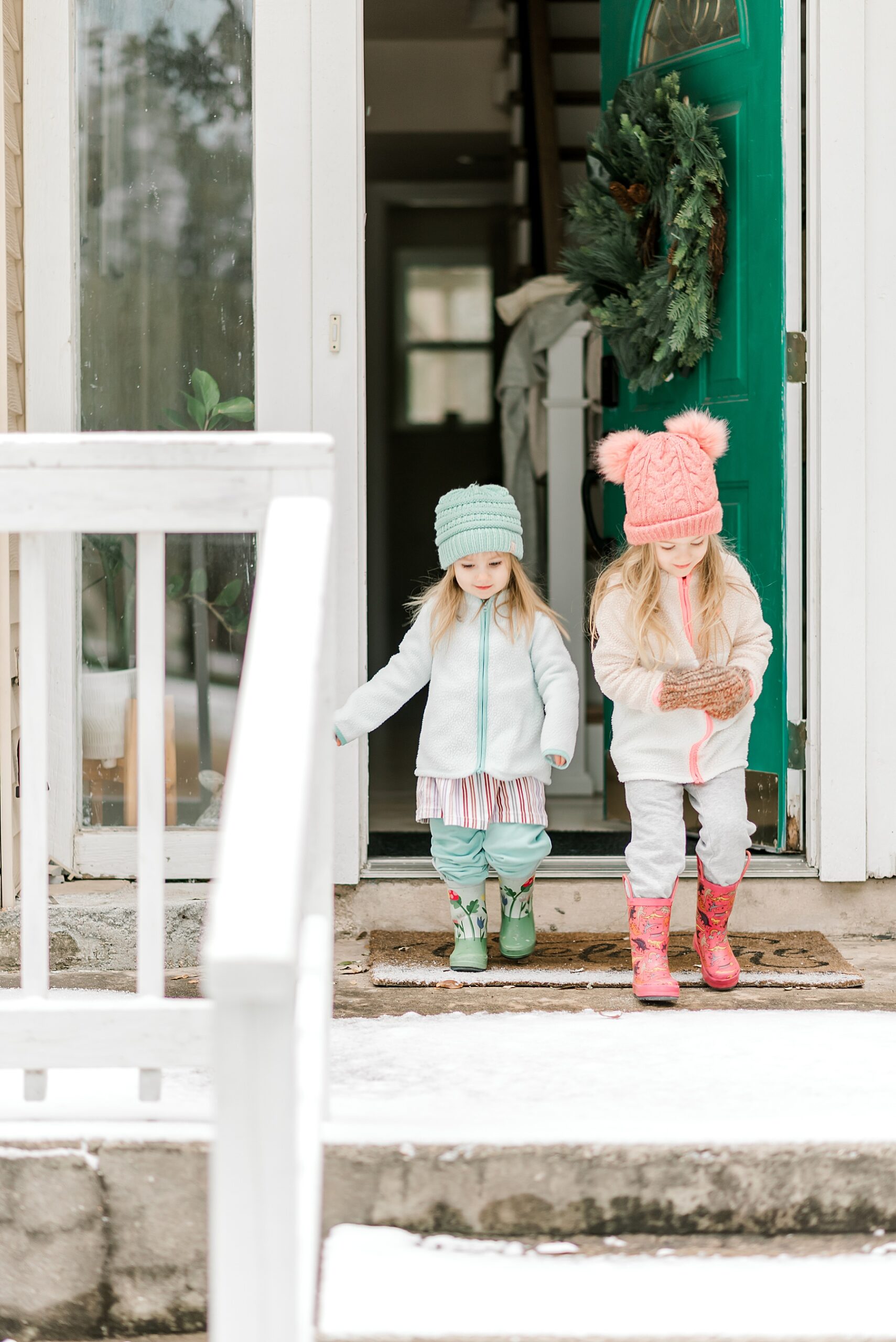 two little girls bundled up in snow gear head outside in the Texas snowstorm