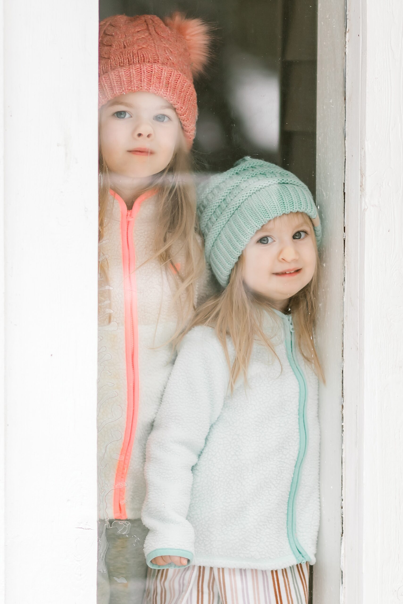 two little girls look out the window at the Texas snow