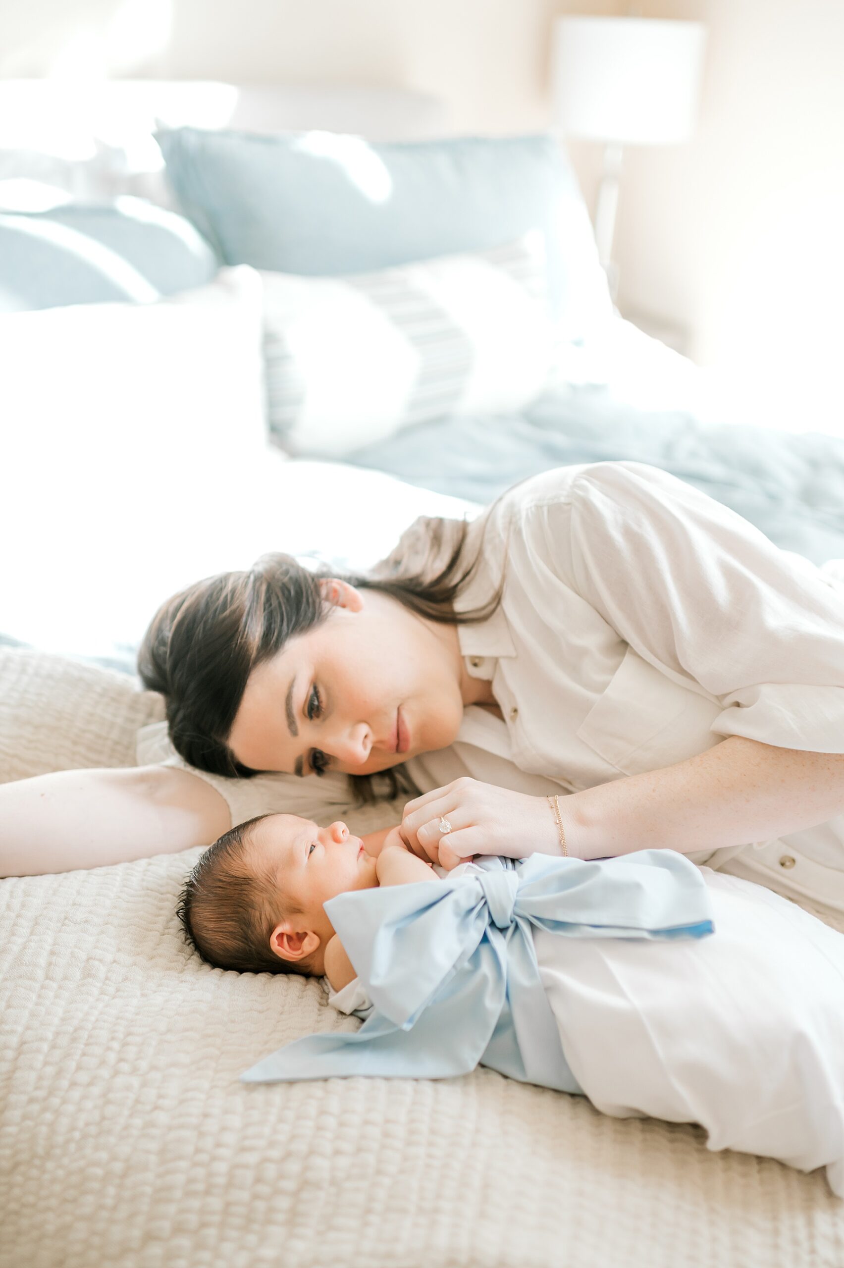 mom lays on bed with newborn son