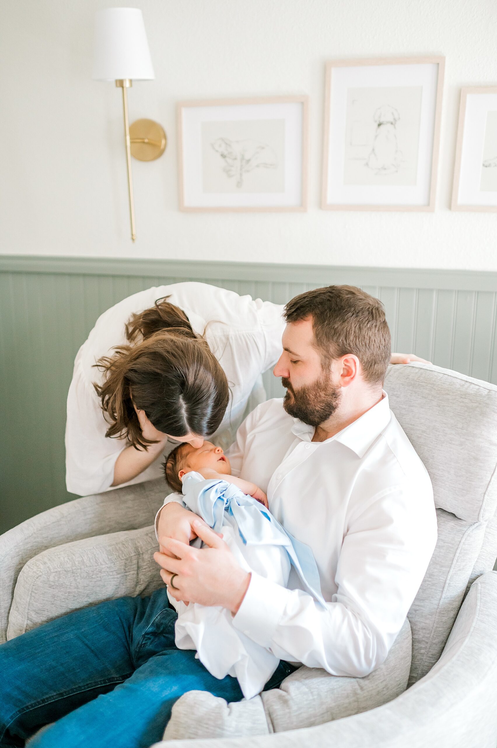 mom kisses baby in dad's arm