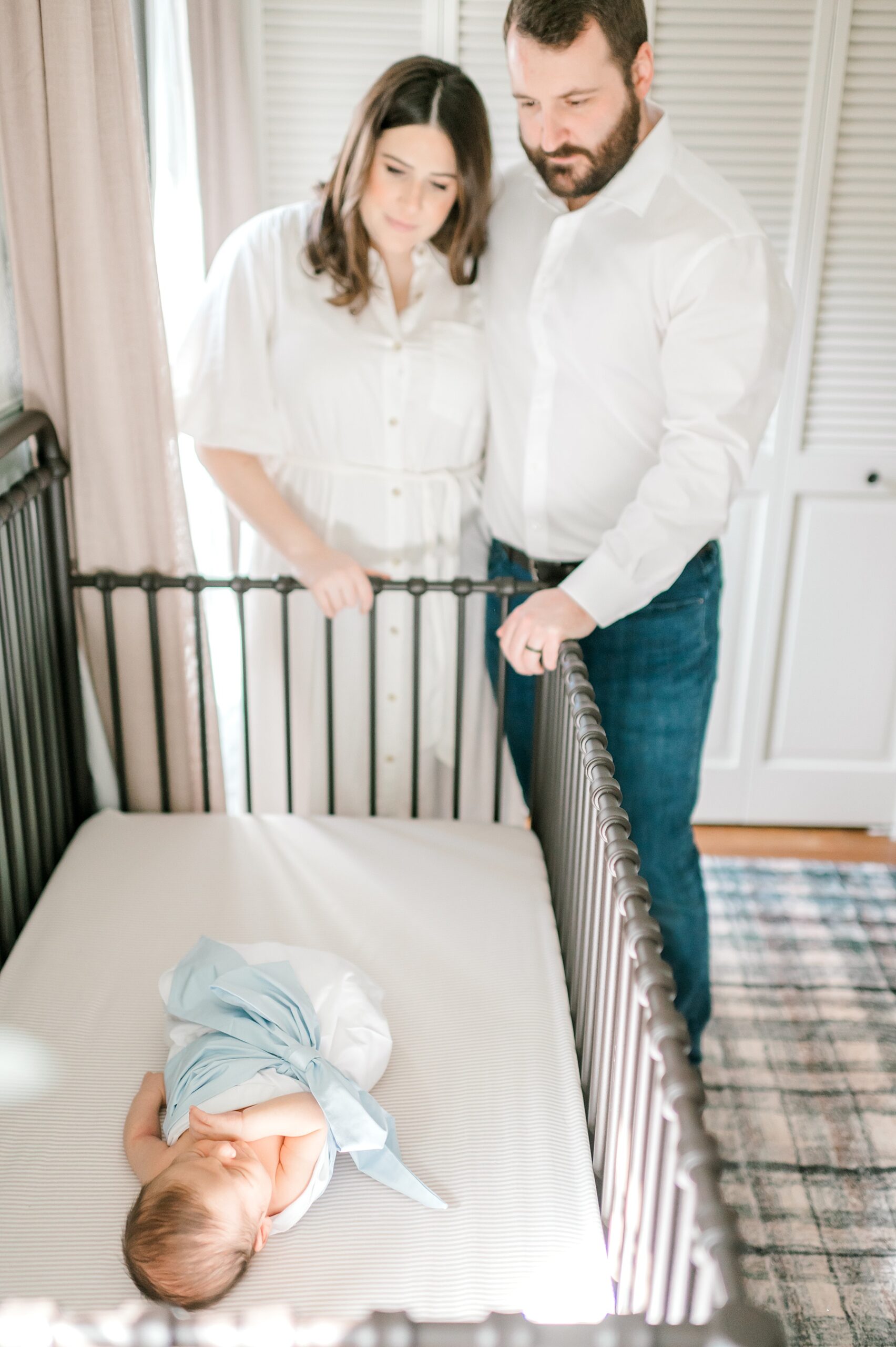 parents look down on newborn sleeping in crib