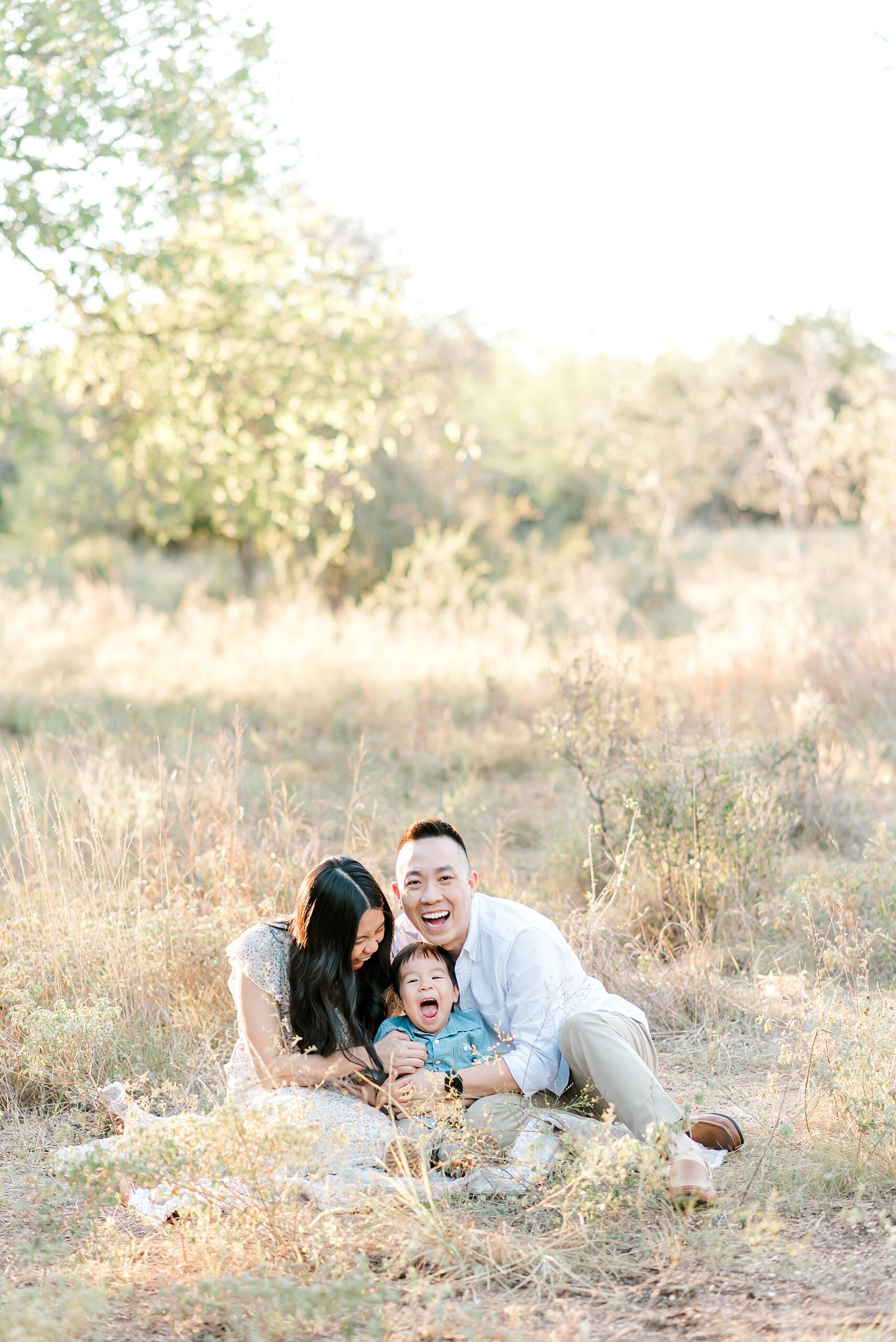 family laughs as they sit together during Phil Hardberger Park Family Session