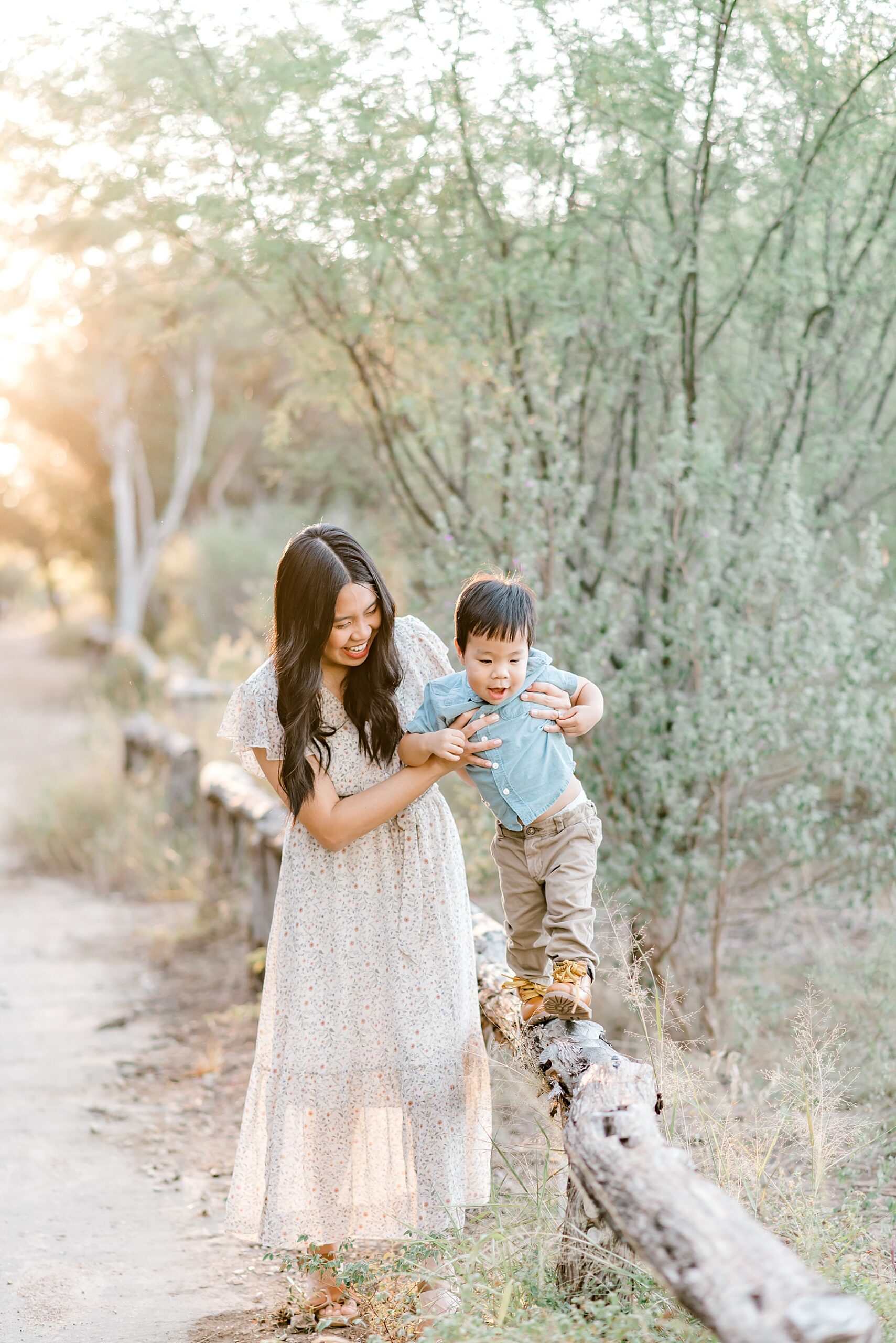 mom helps son walk across log