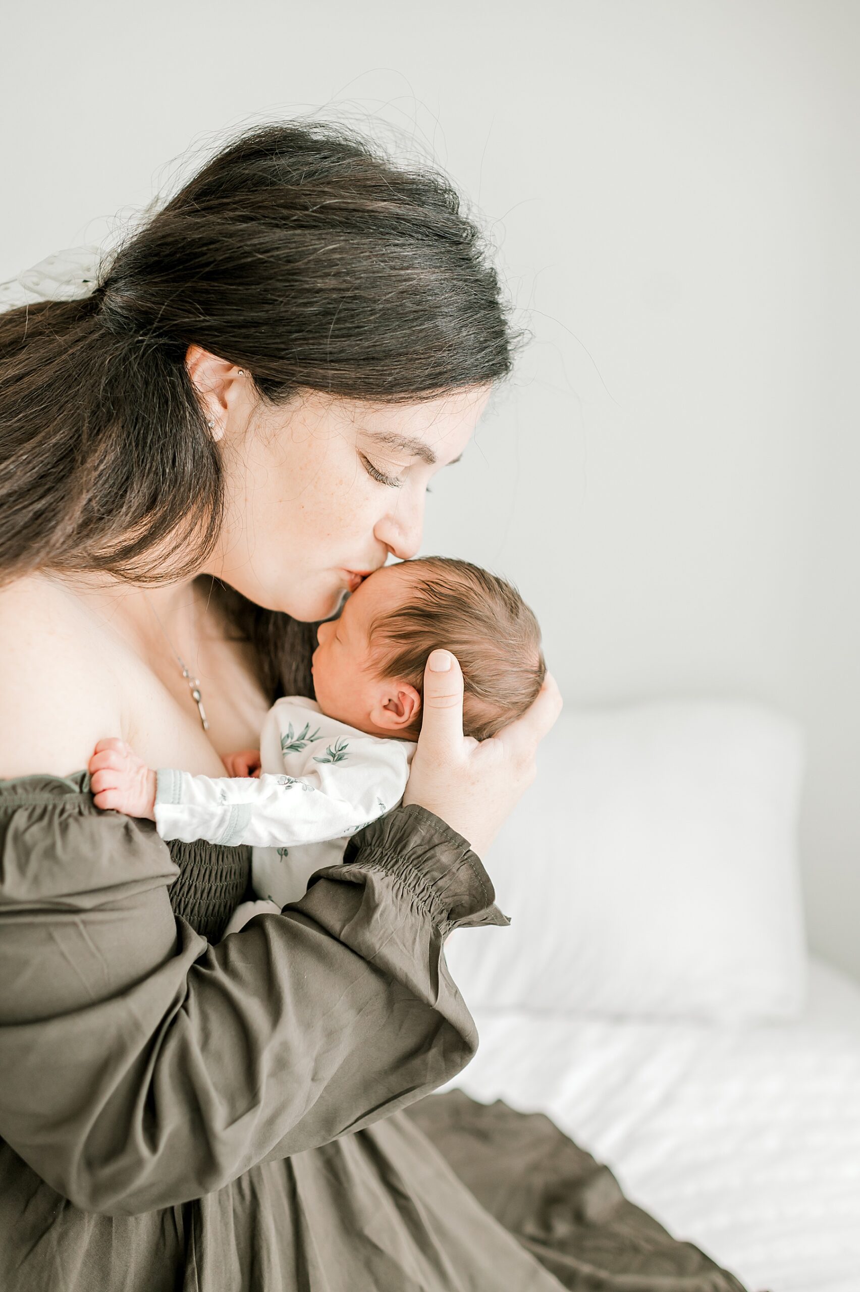 mom kisses baby boy's forehead during December Studio Newborn Session