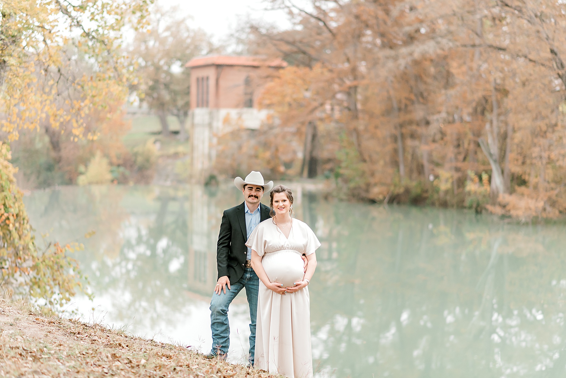 expectant couple stand by water at Max Starcke Park