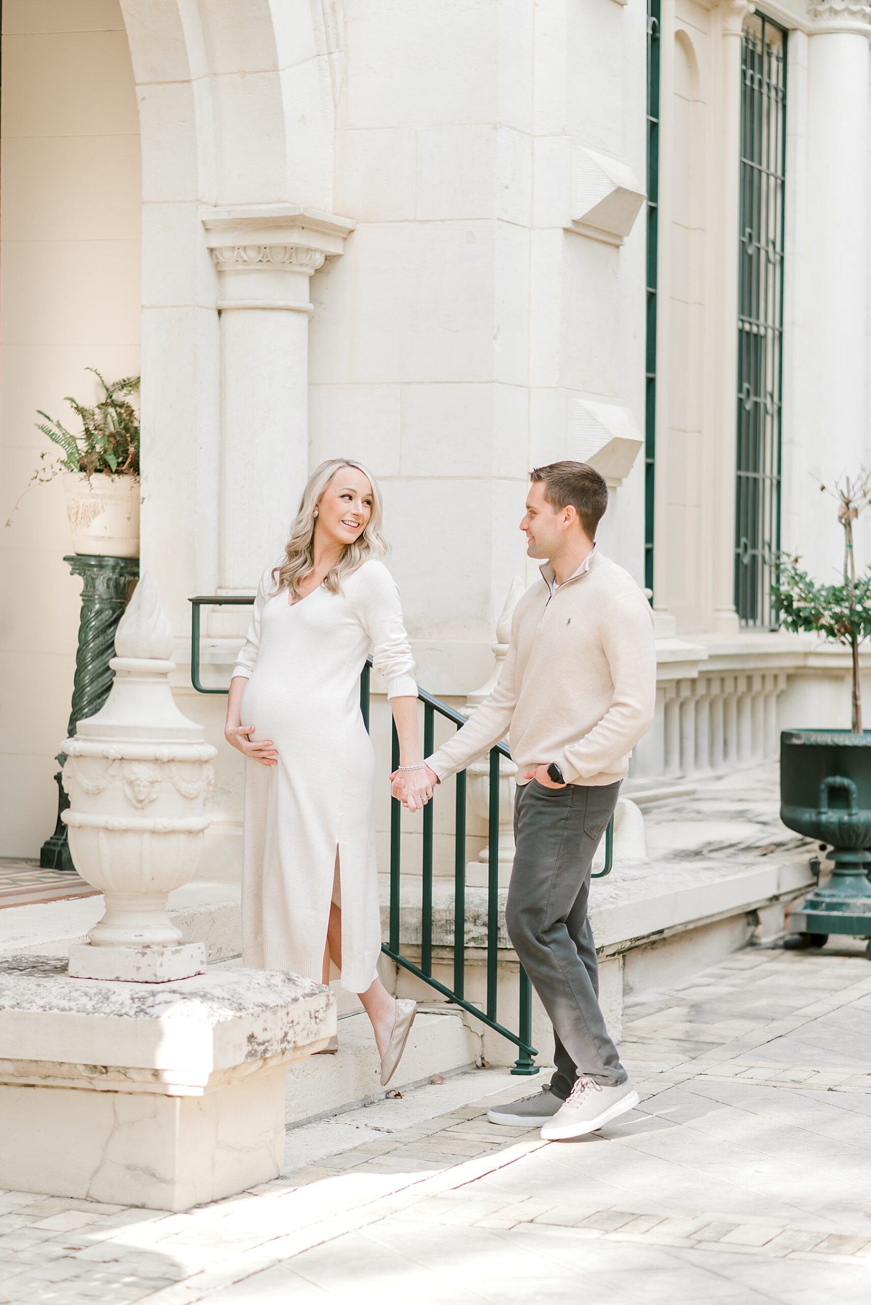 couple hold hands as they walk up stairs during Downtown San Antonio Maternity Session