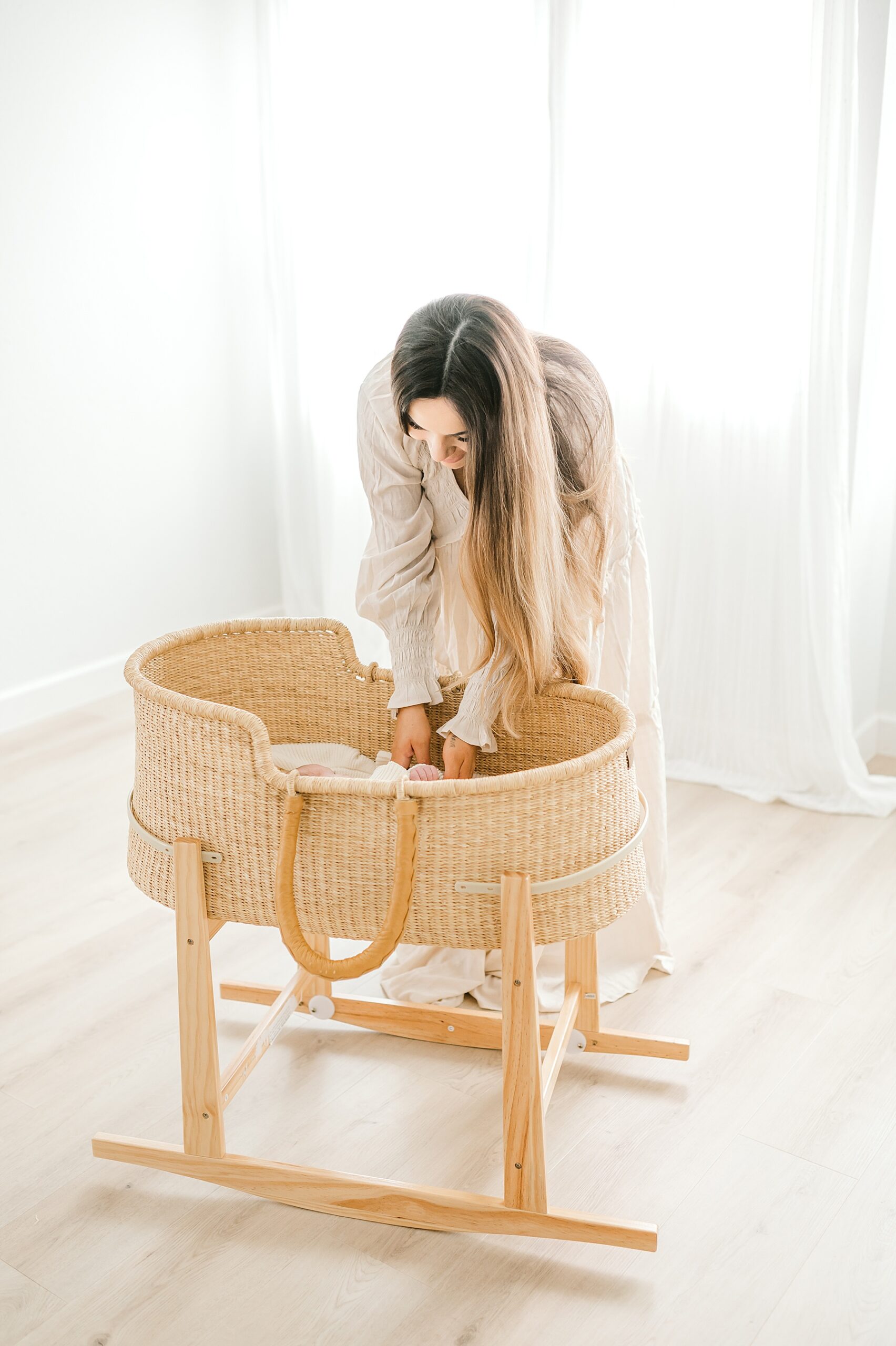 mom places newborn in bassinet during studio newborn session 