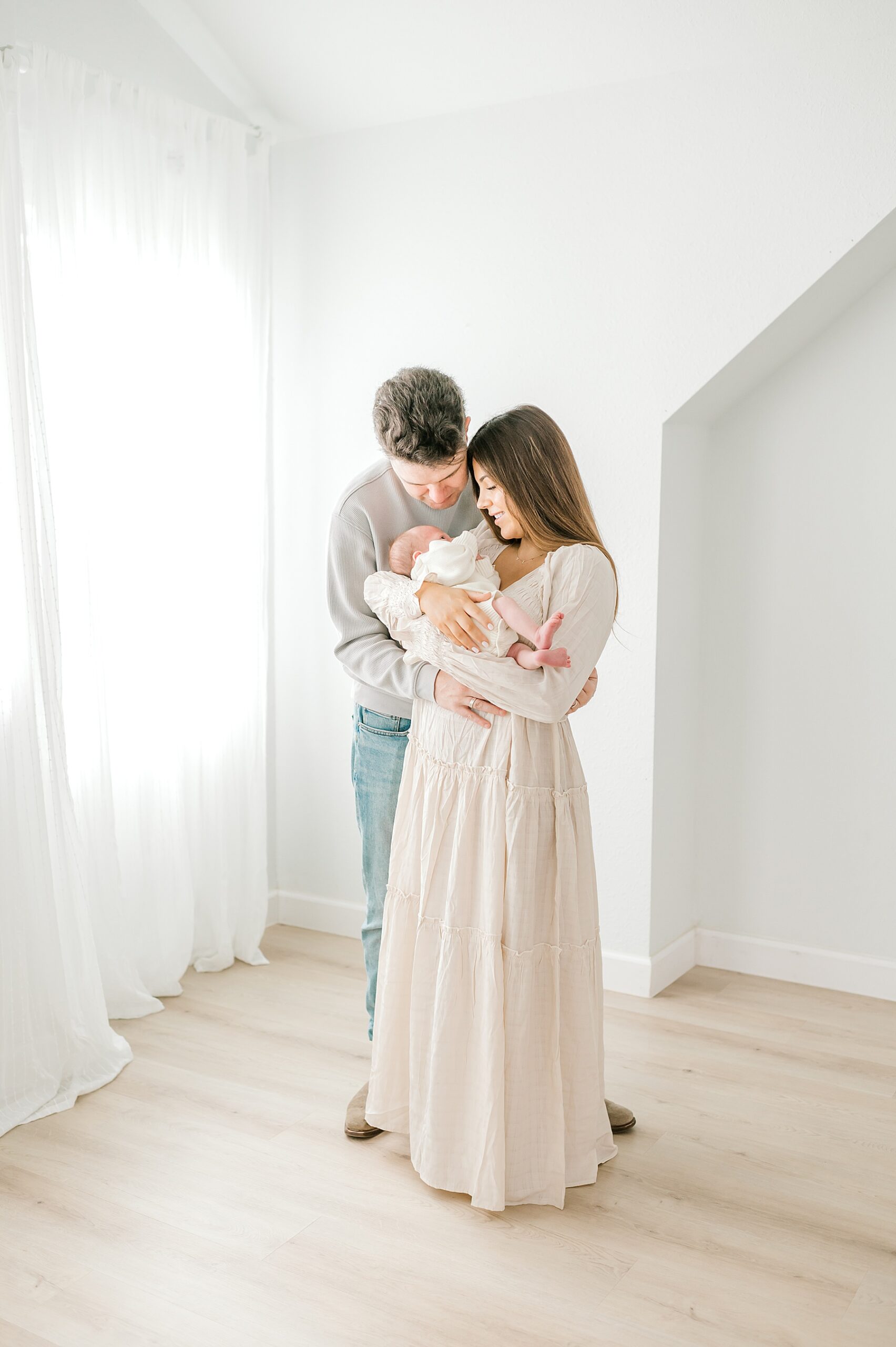 mom and dad look down lovingly at their newborn son during Texas studio session 