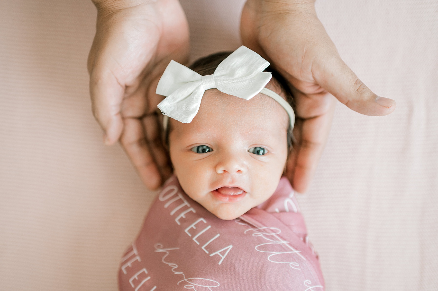 newborn girl with white bow headband looks up at camera | Why Awake Babies Are Just As Perfect