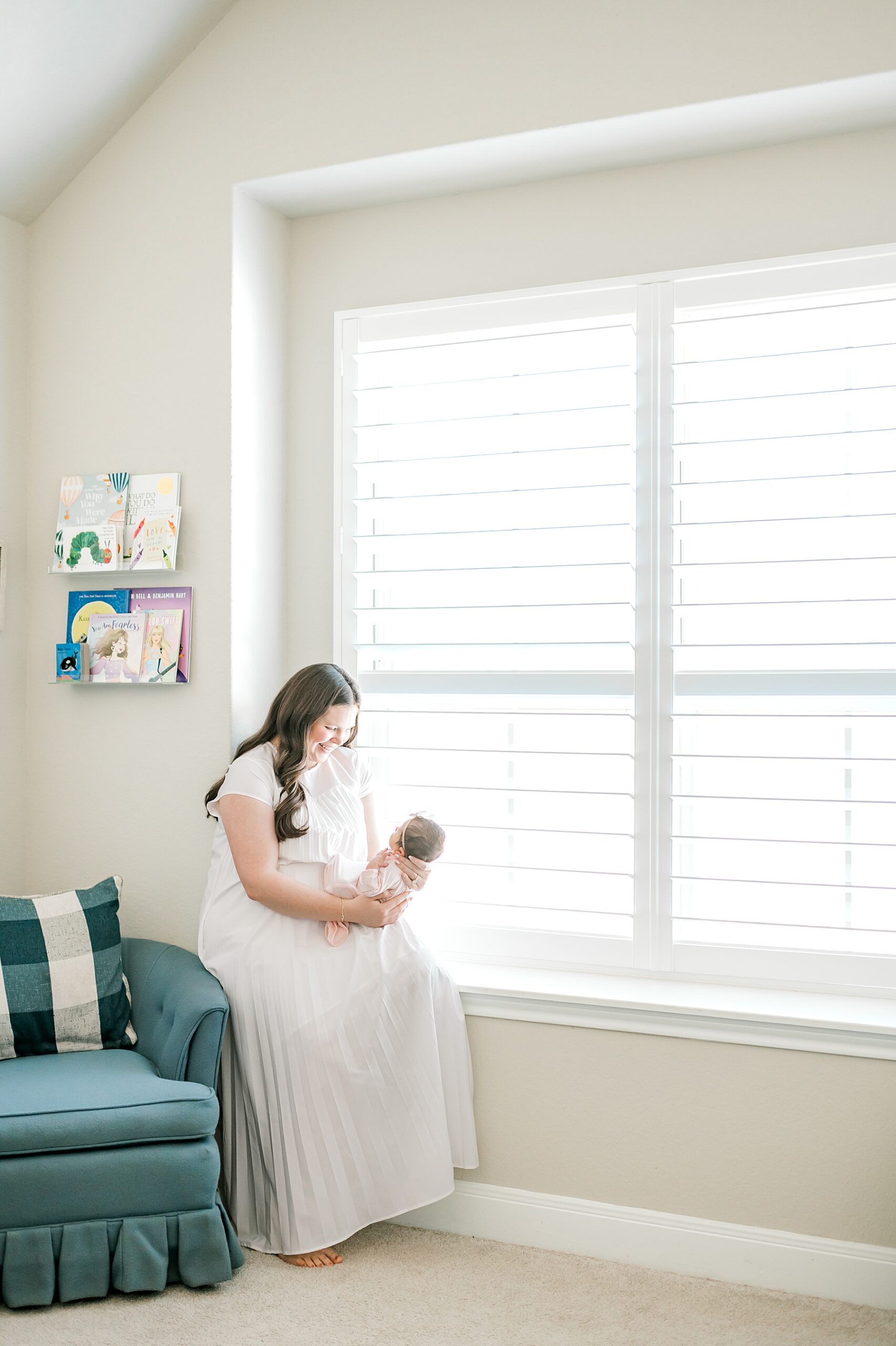 mom holding newborn by window