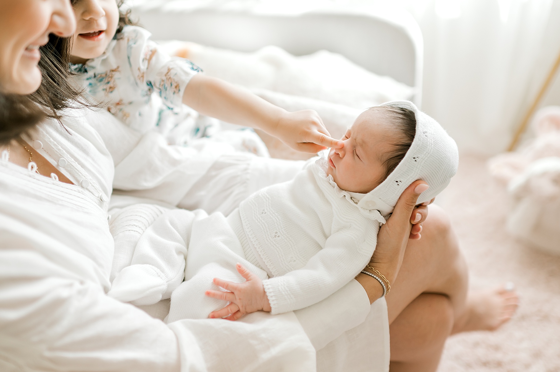 mom and daughter look at newborn girl.