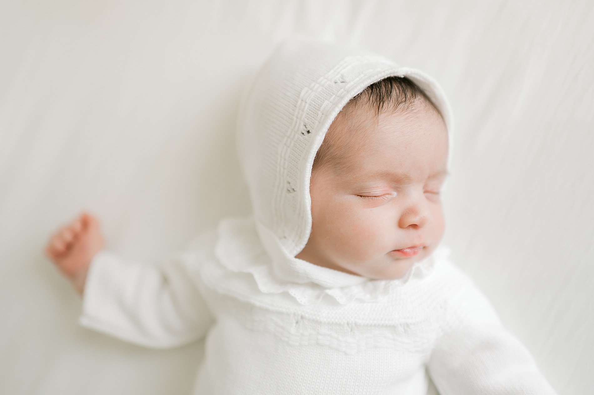 newborn in soft white outfit and hat | What to Wear for Your Lifestyle Newborn Session