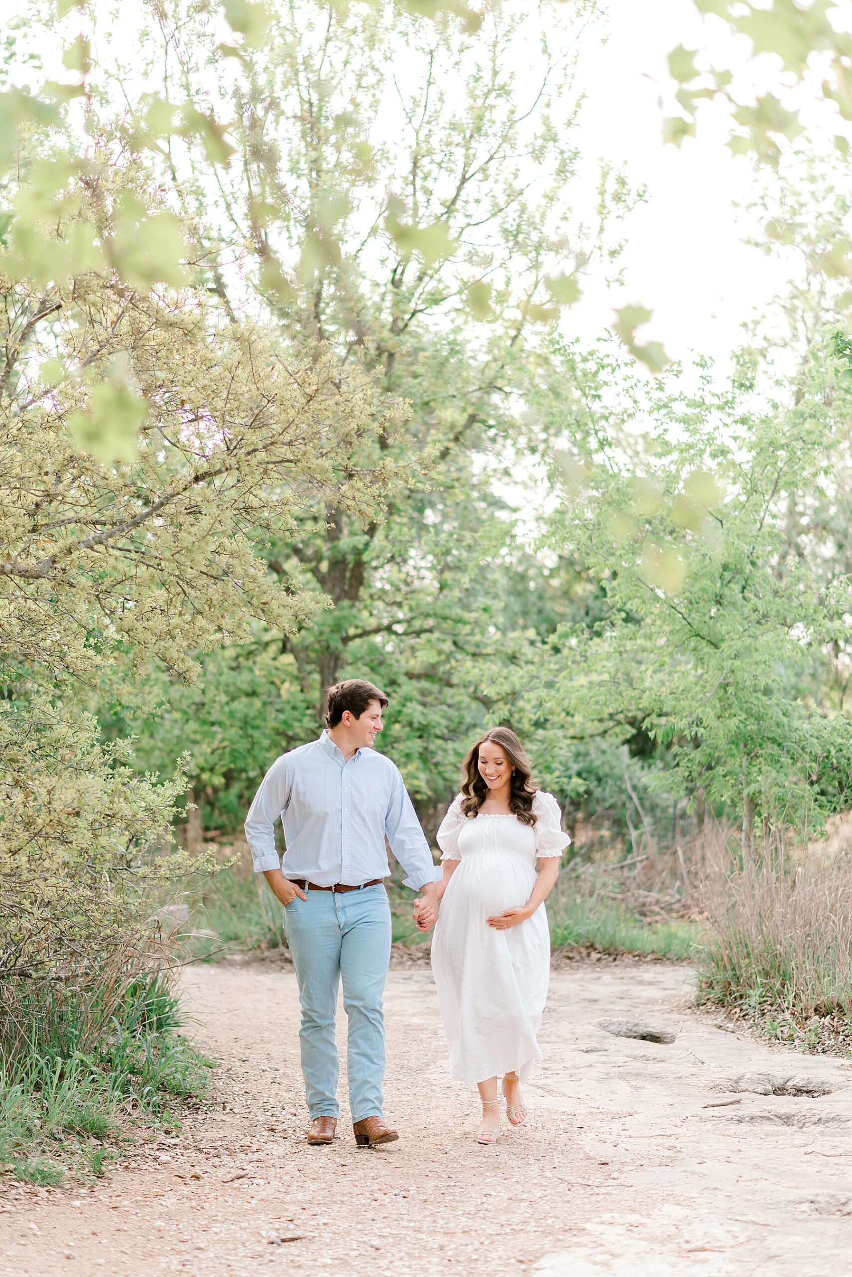 expectant parents walk together holding hands