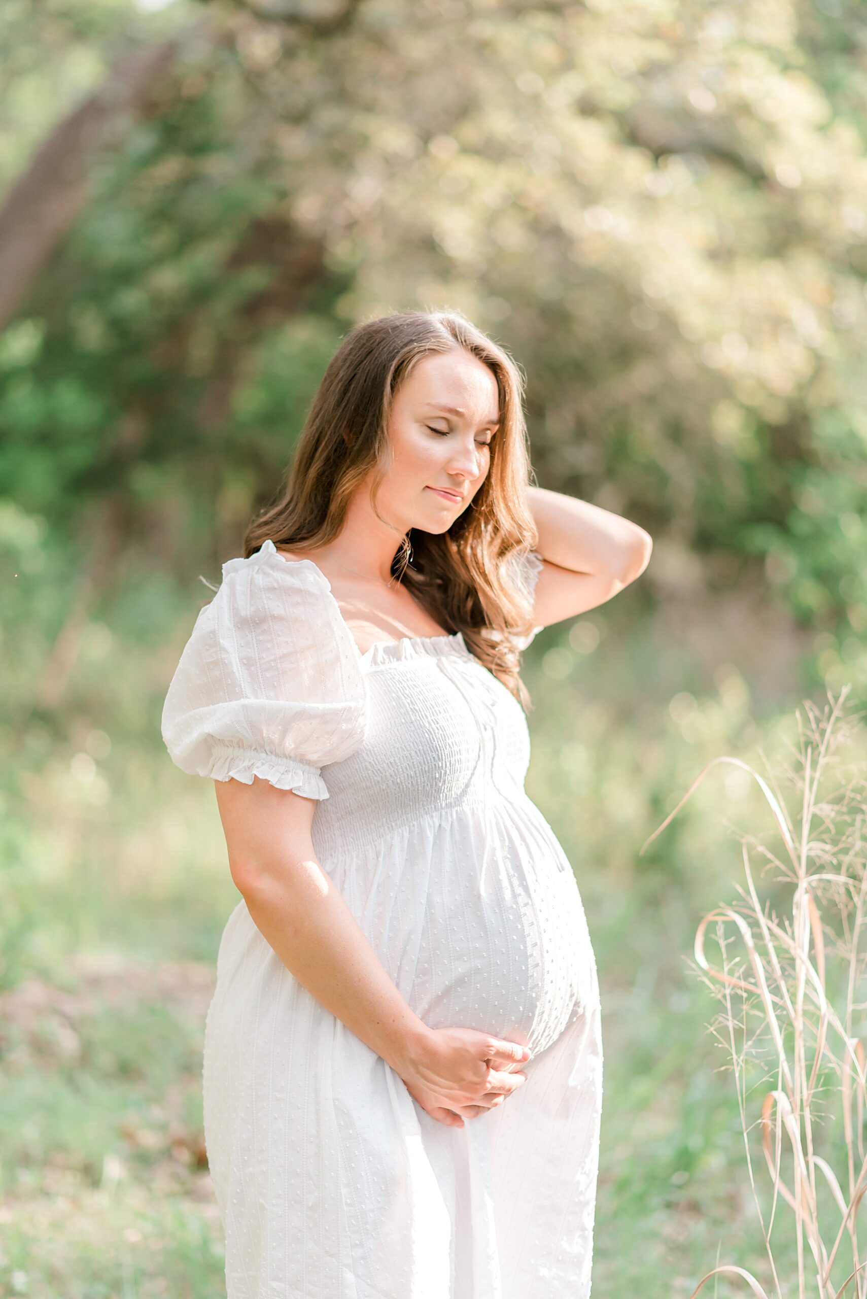 expectant mom in white dress holds baby bump