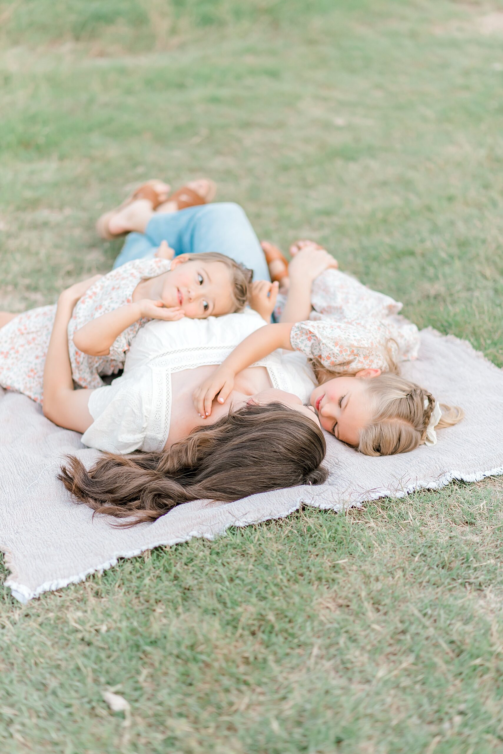 two girls lay with their mom on a blanket at Crescent Bend Nature Park
