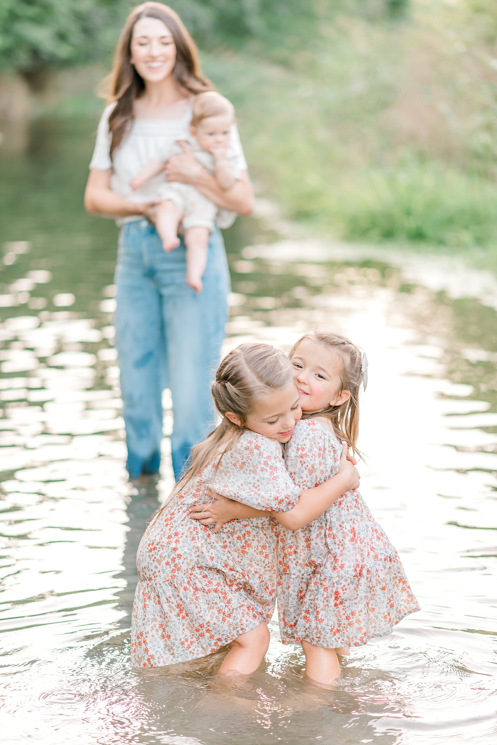 sisters hug as they play in water | How to Choose the Right Season and Setting for Family Photos | Crescent Bend Family Session by the River