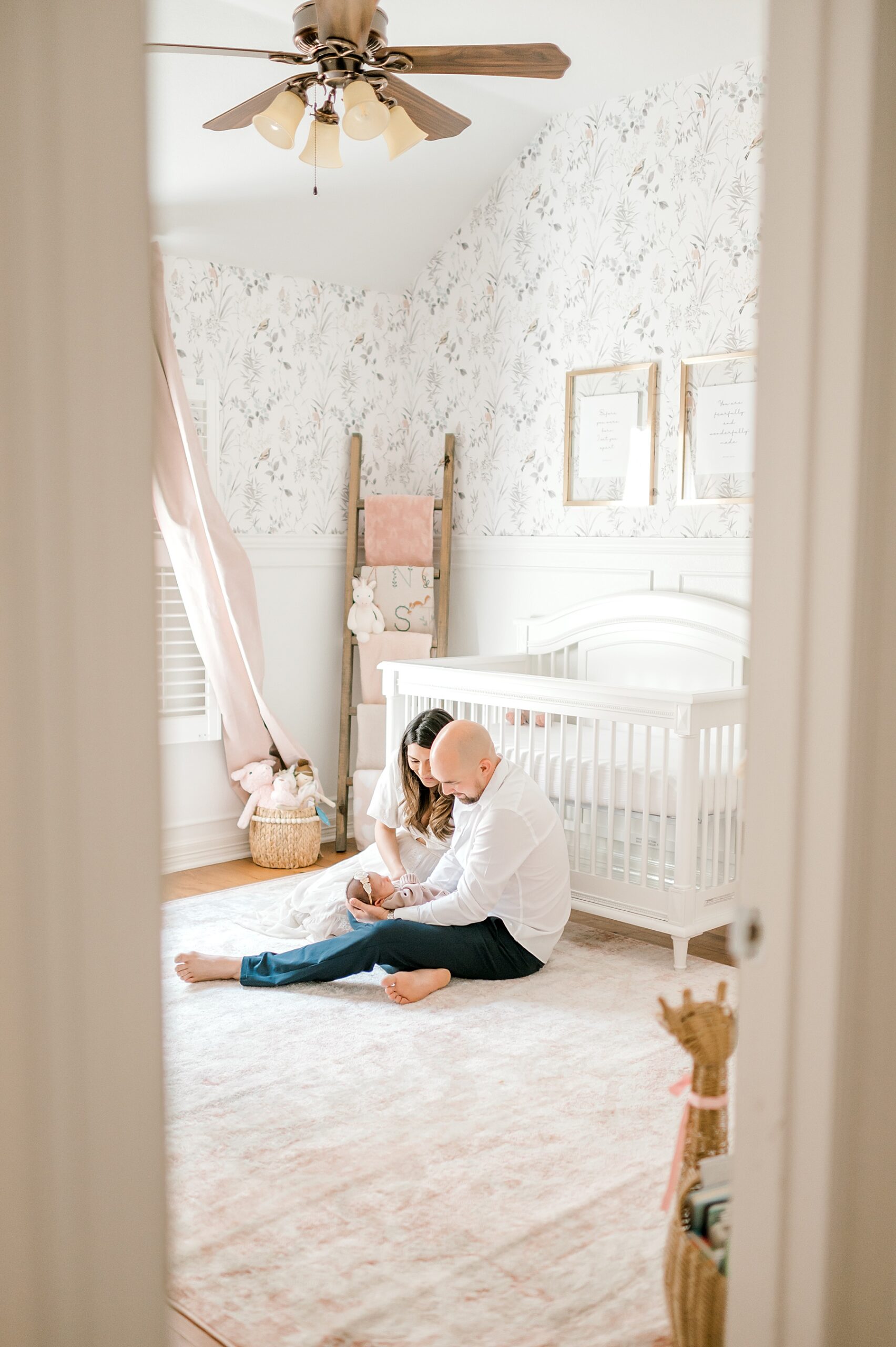 parents sit on floor of nursery with newborn girl