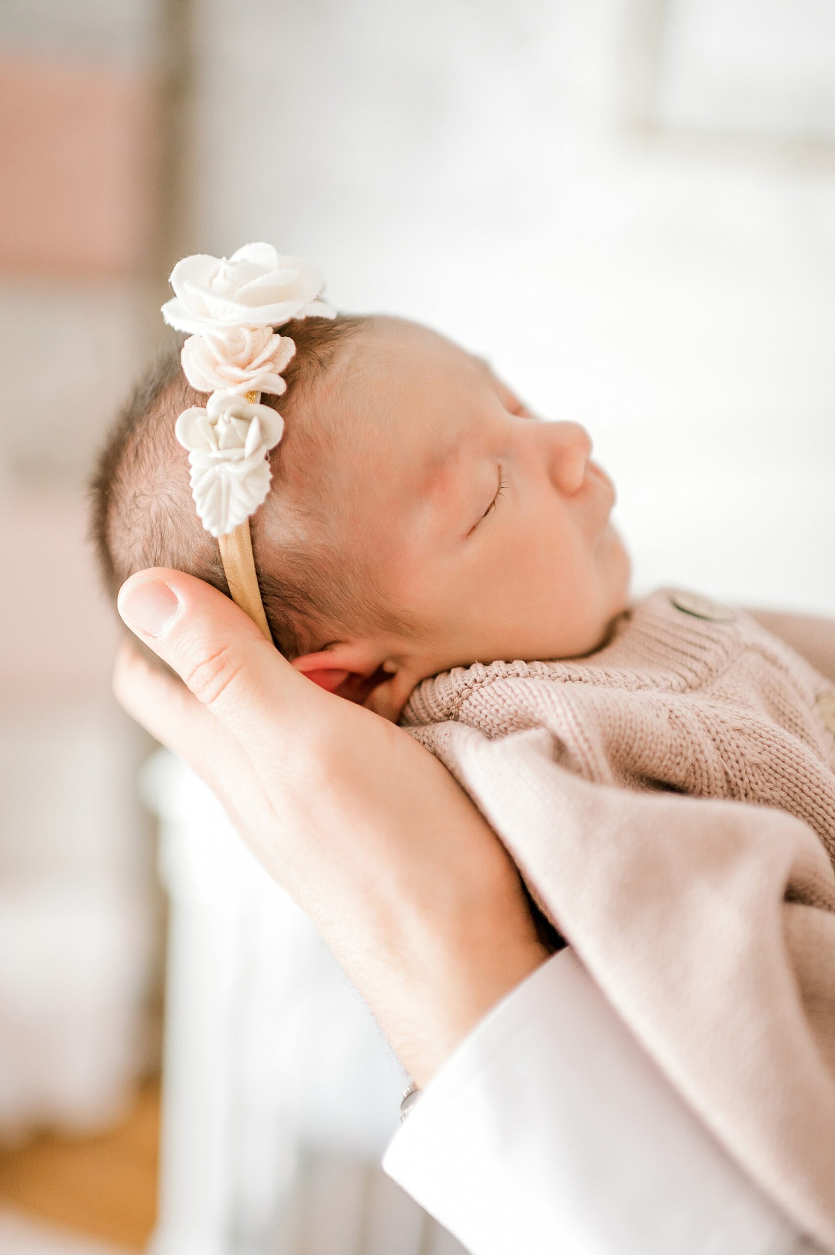 newborn girl with headband in arms of parents