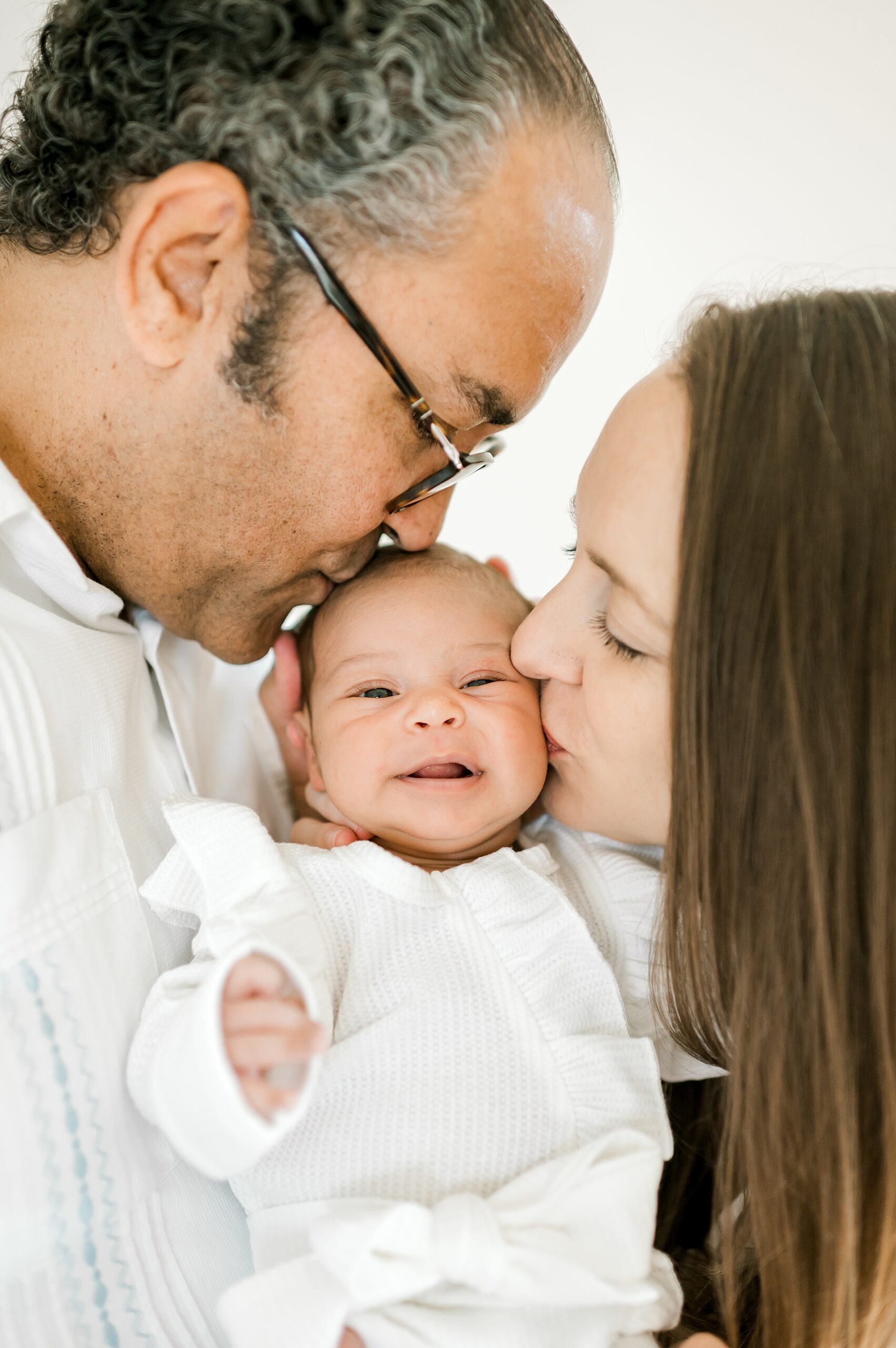 parents kiss their newborn girl