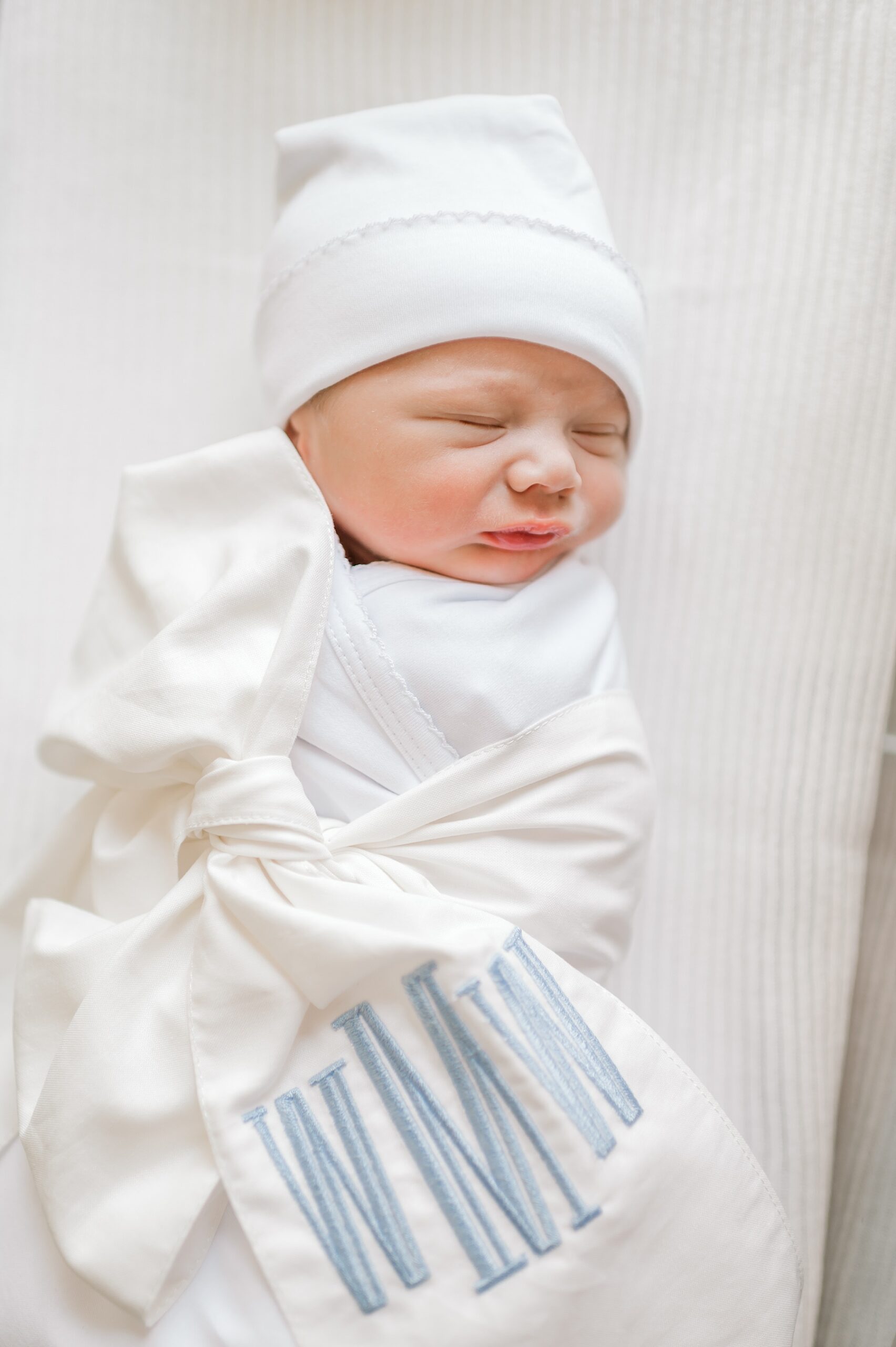 Newborn in white hat and personalized, monogram swaddle