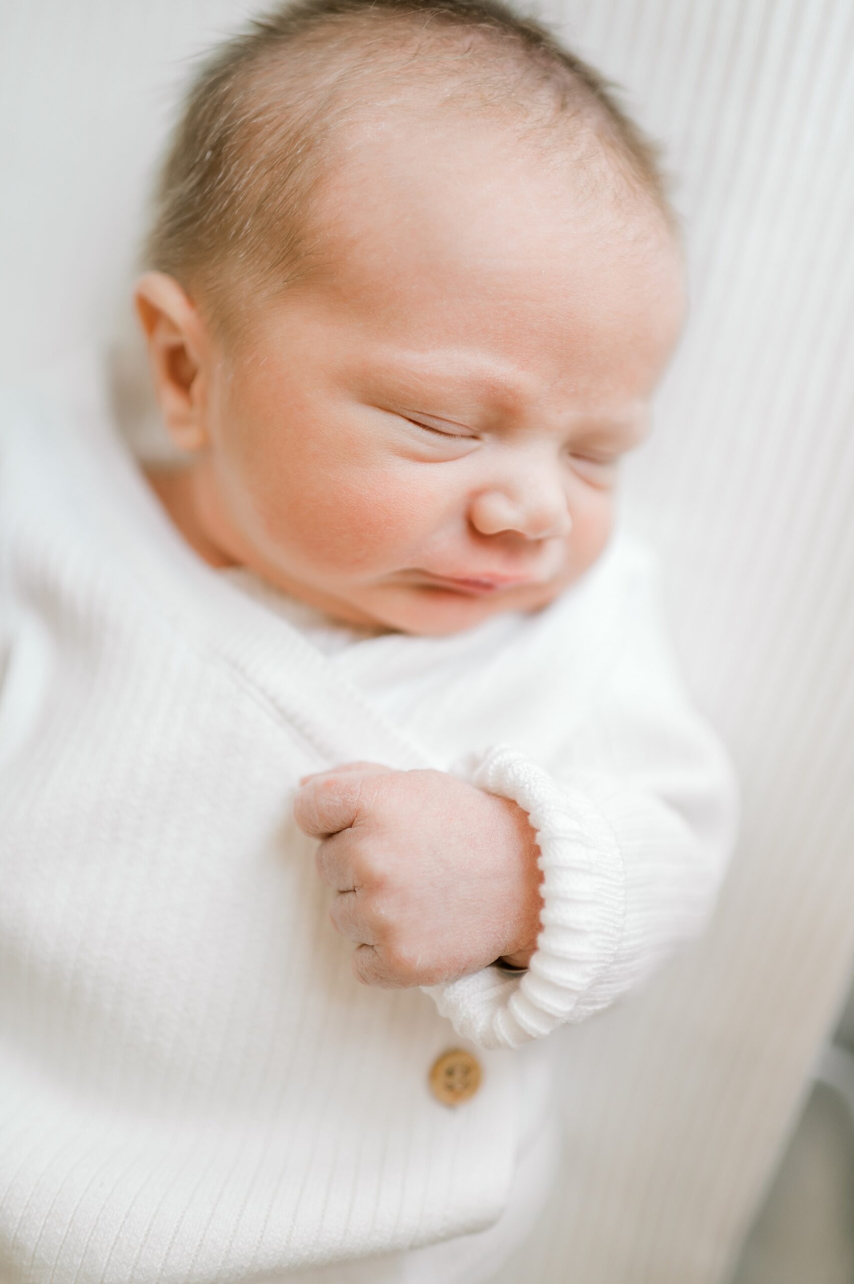 sleepy newborn in white sweater
