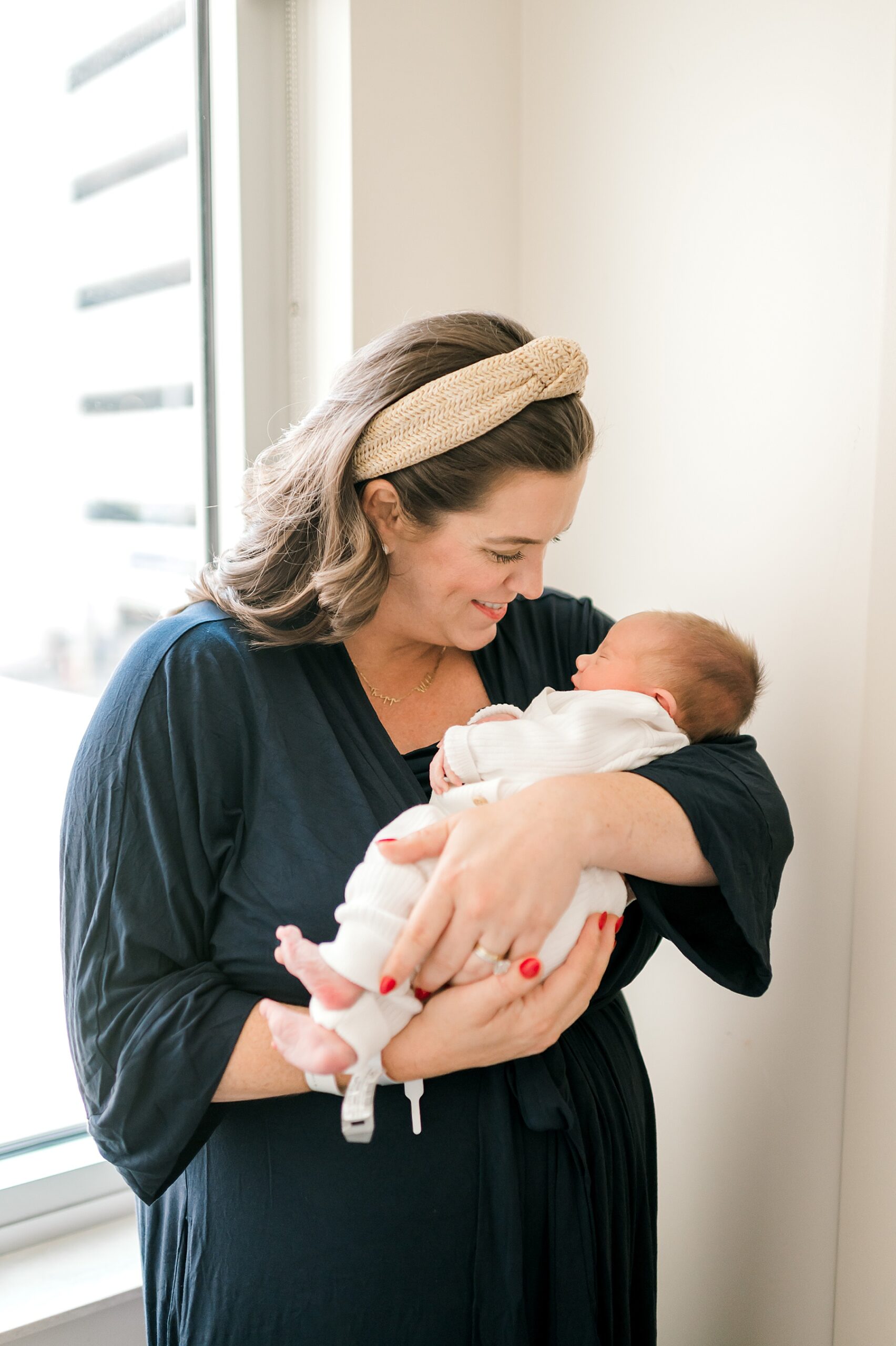 mom holds newborn by window
