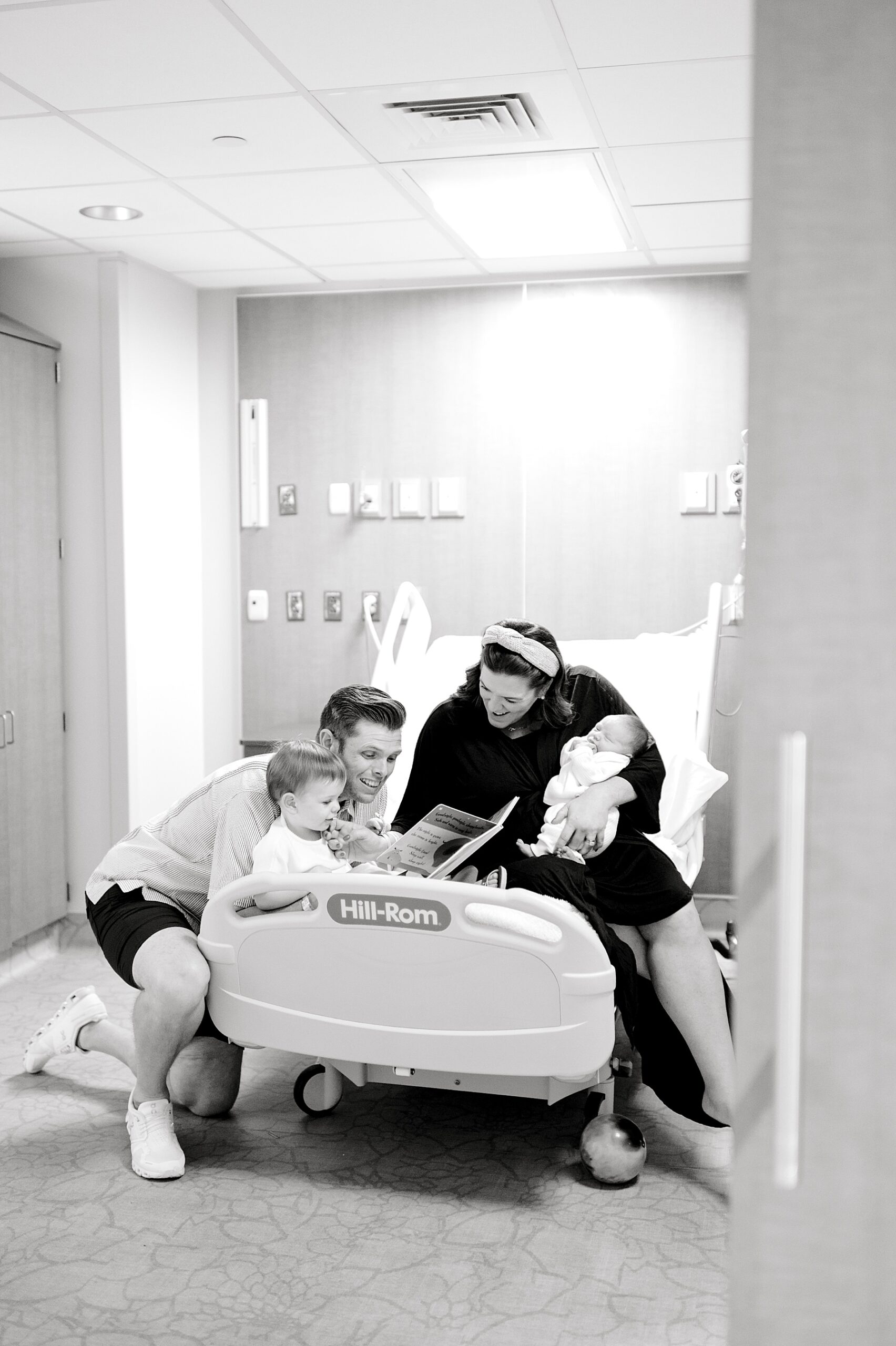 family of four sit in hospital bed reading book during fresh 48 session
