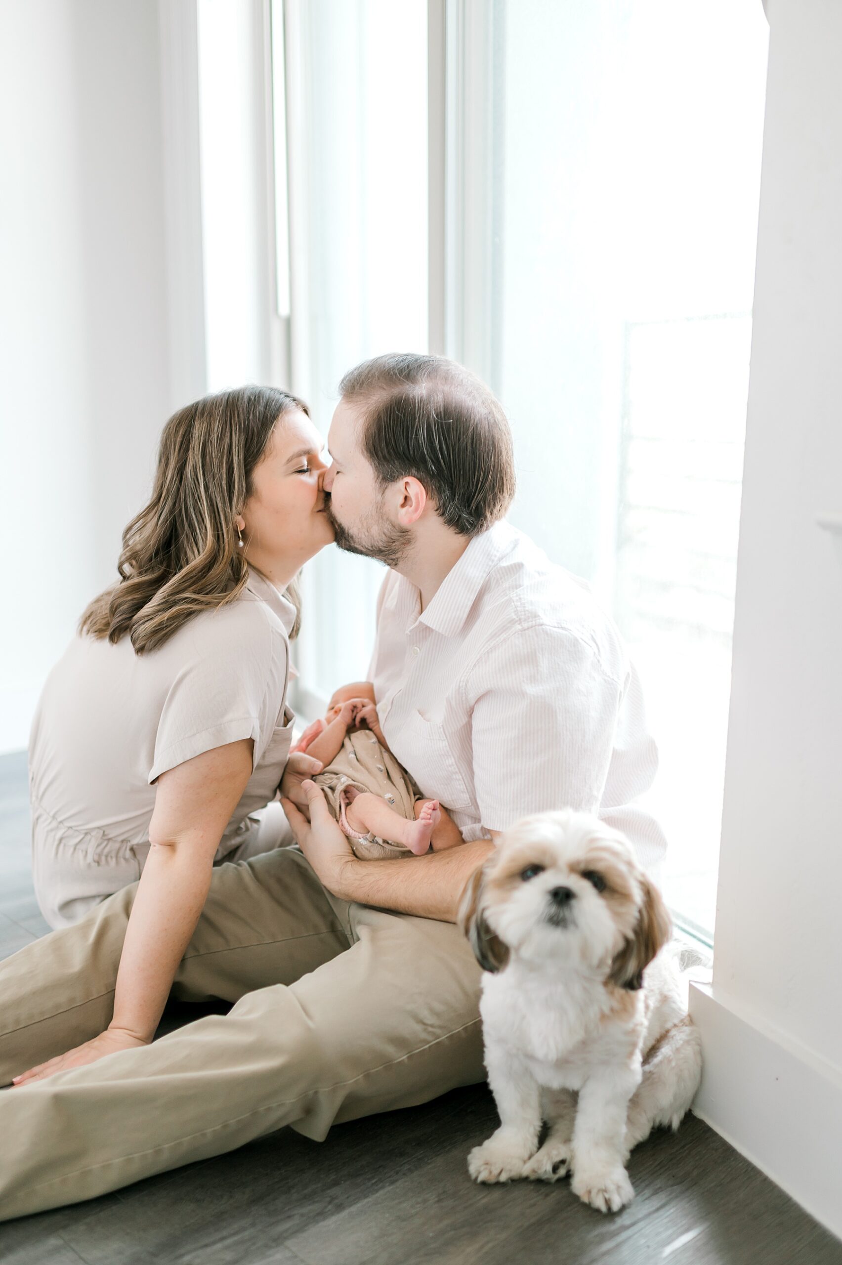 parents kiss while holding newborn