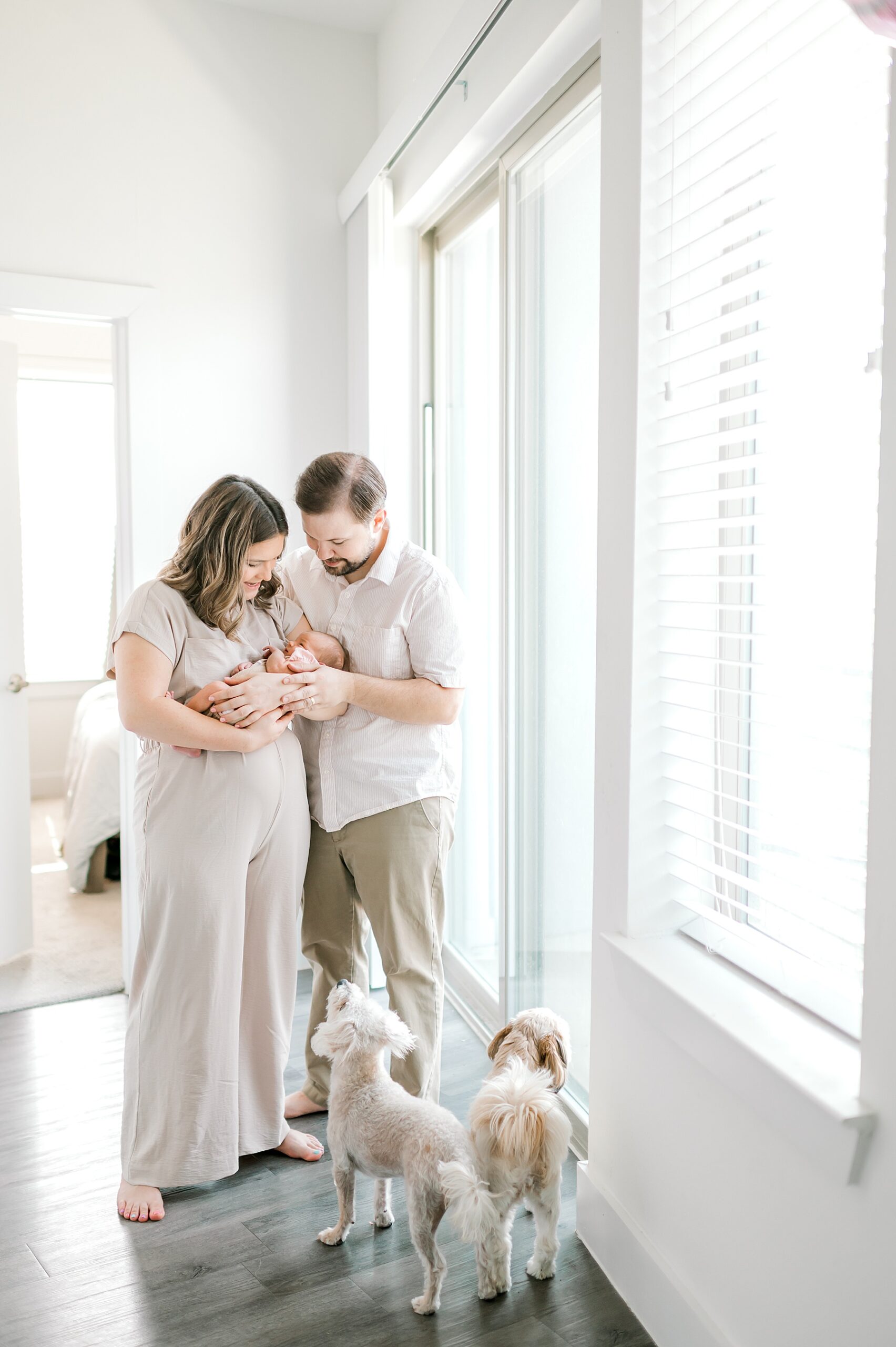 parents hold newborn close by window