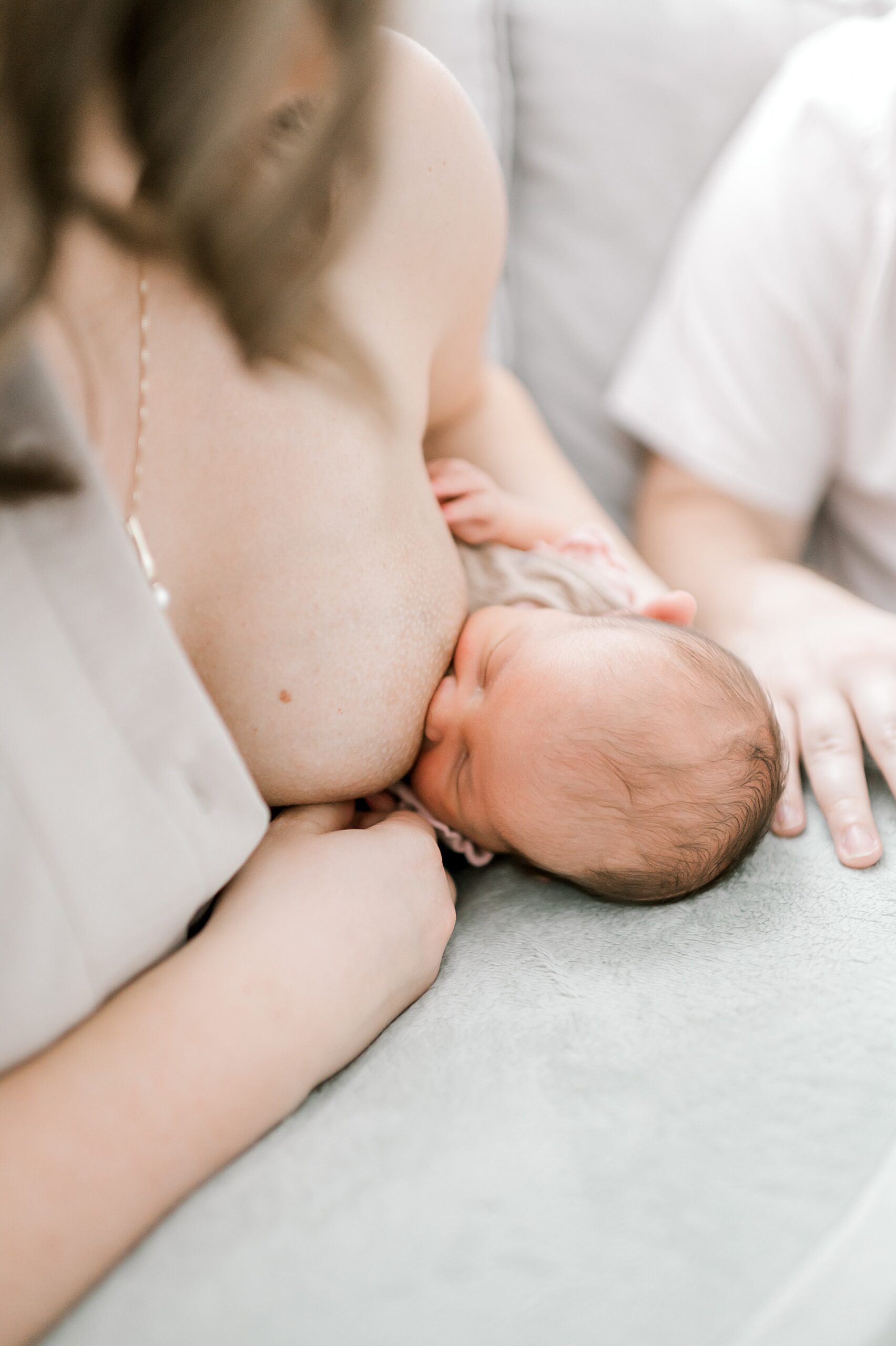 mom nurses newborn while sitting on couch