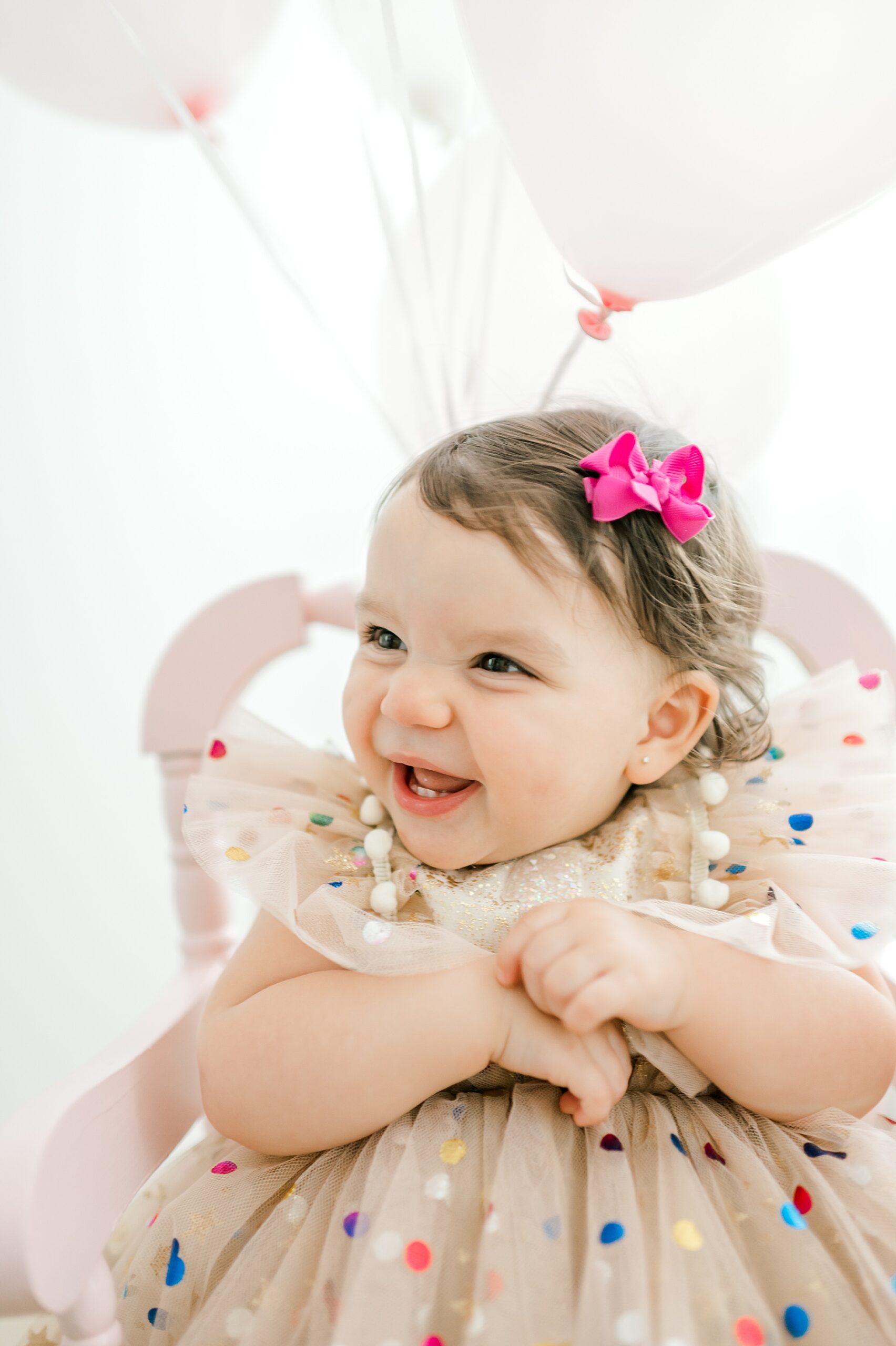 one year old girl with bow in hair with confetti dress