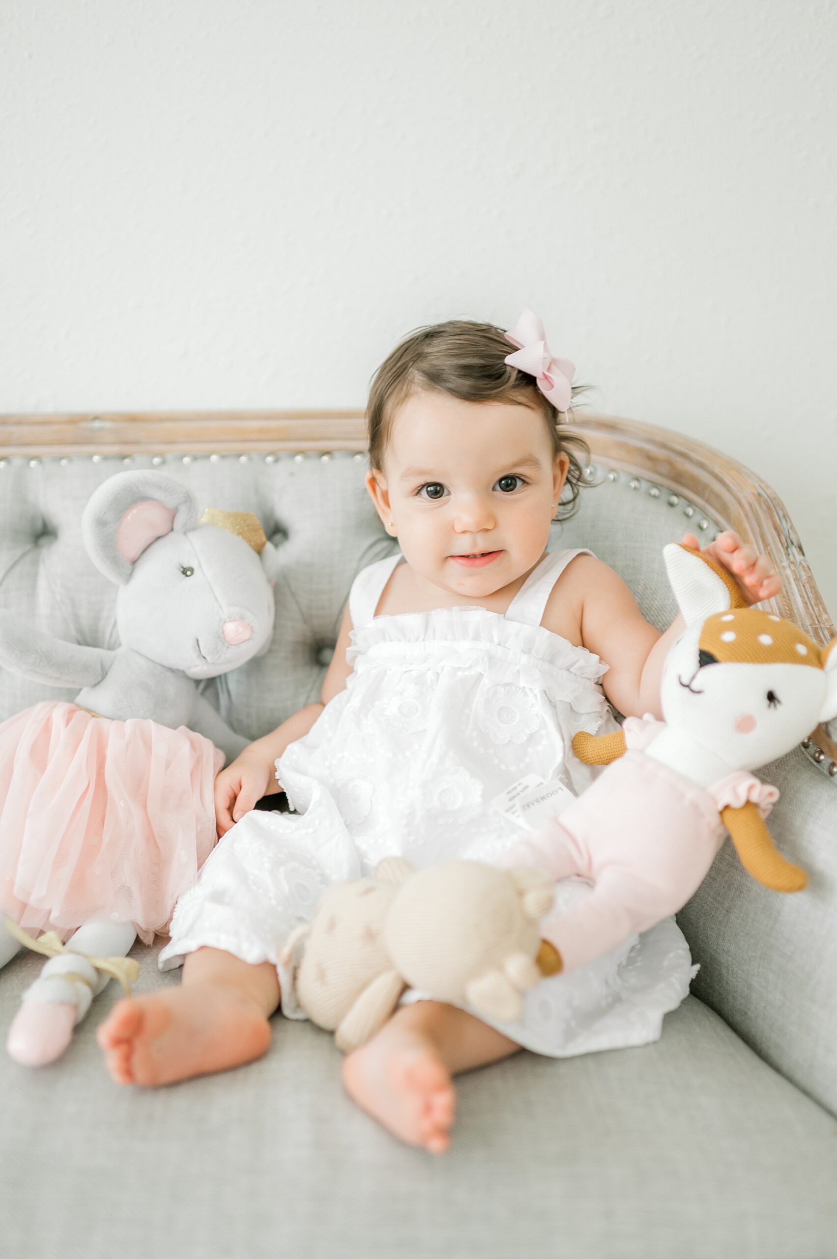 little girl in white dress with all stuffed animals