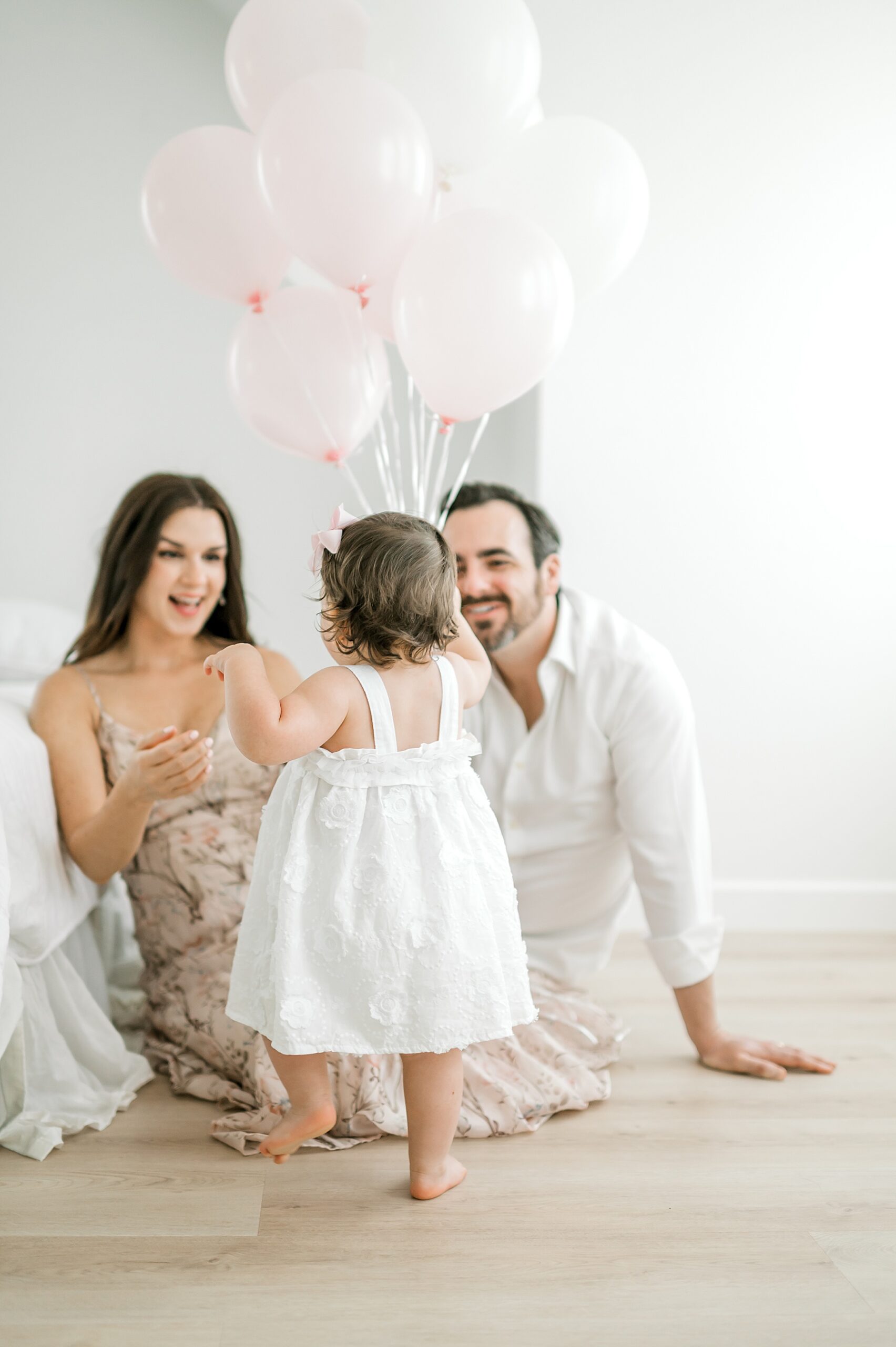little girl walks over to parents holding balloons