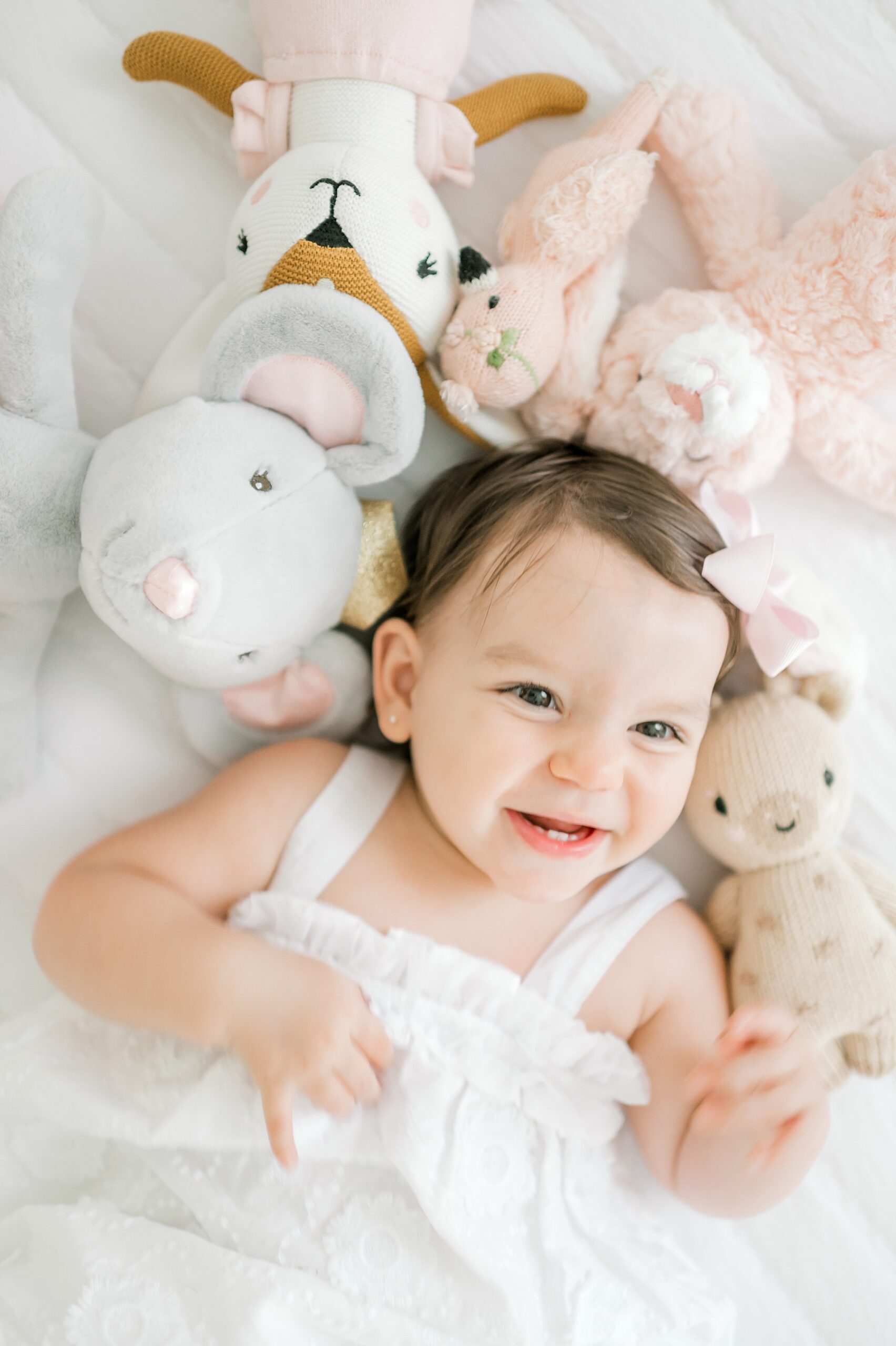 sweet little girl lays with stuffed animals