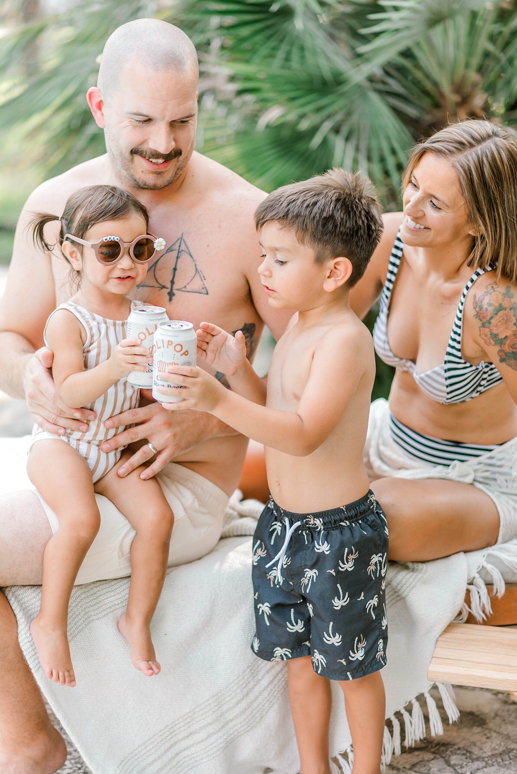 family of four sits in sunshine during Backyard Pool Party Summer Family Session