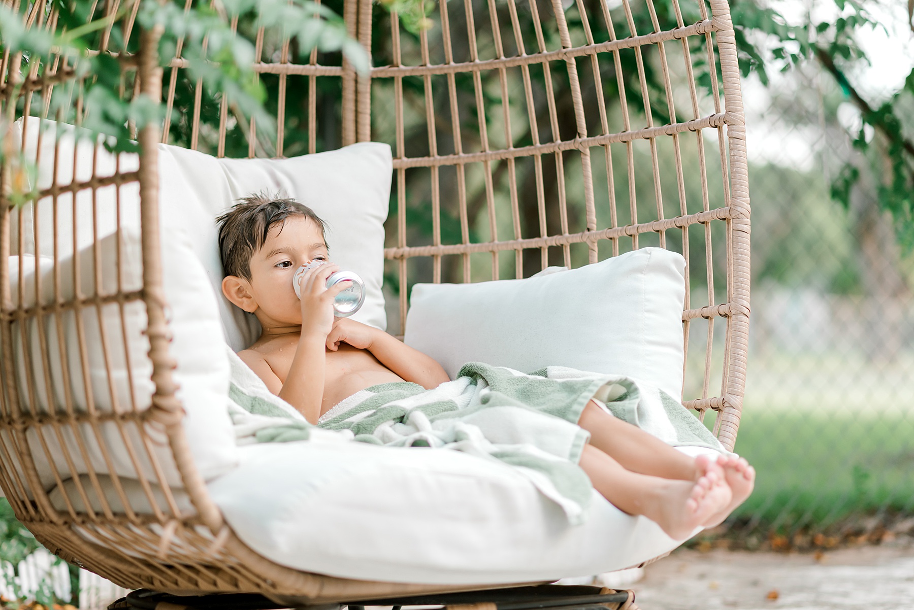 little boy sits in chair outside drinking olipop